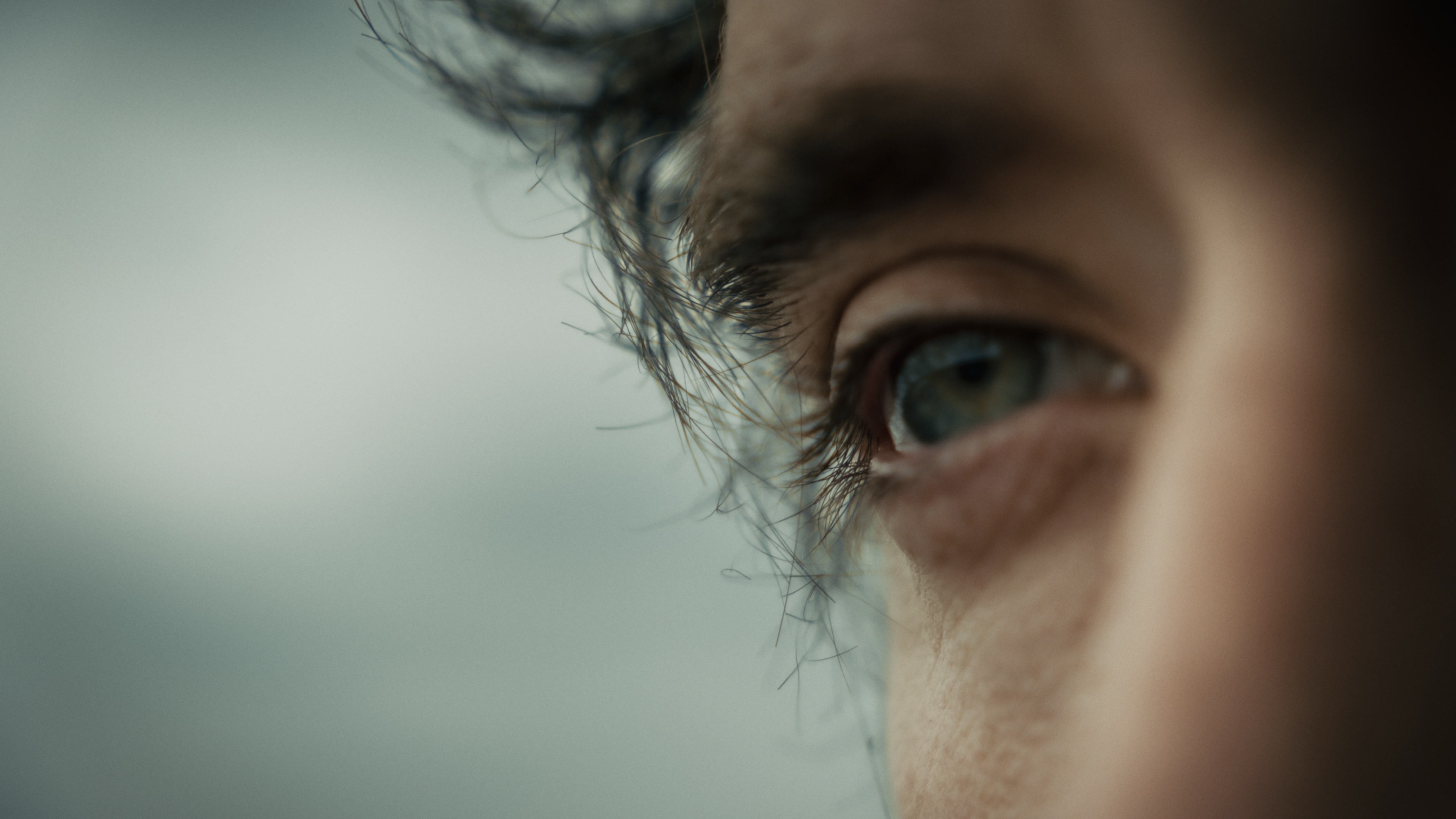 Extreme close-up of a man's eye and wet hair, detailed artistic portrait.