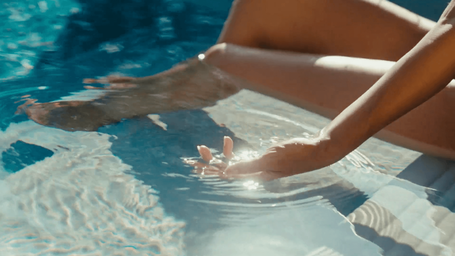 A hand shining in the water of a pool in the sun