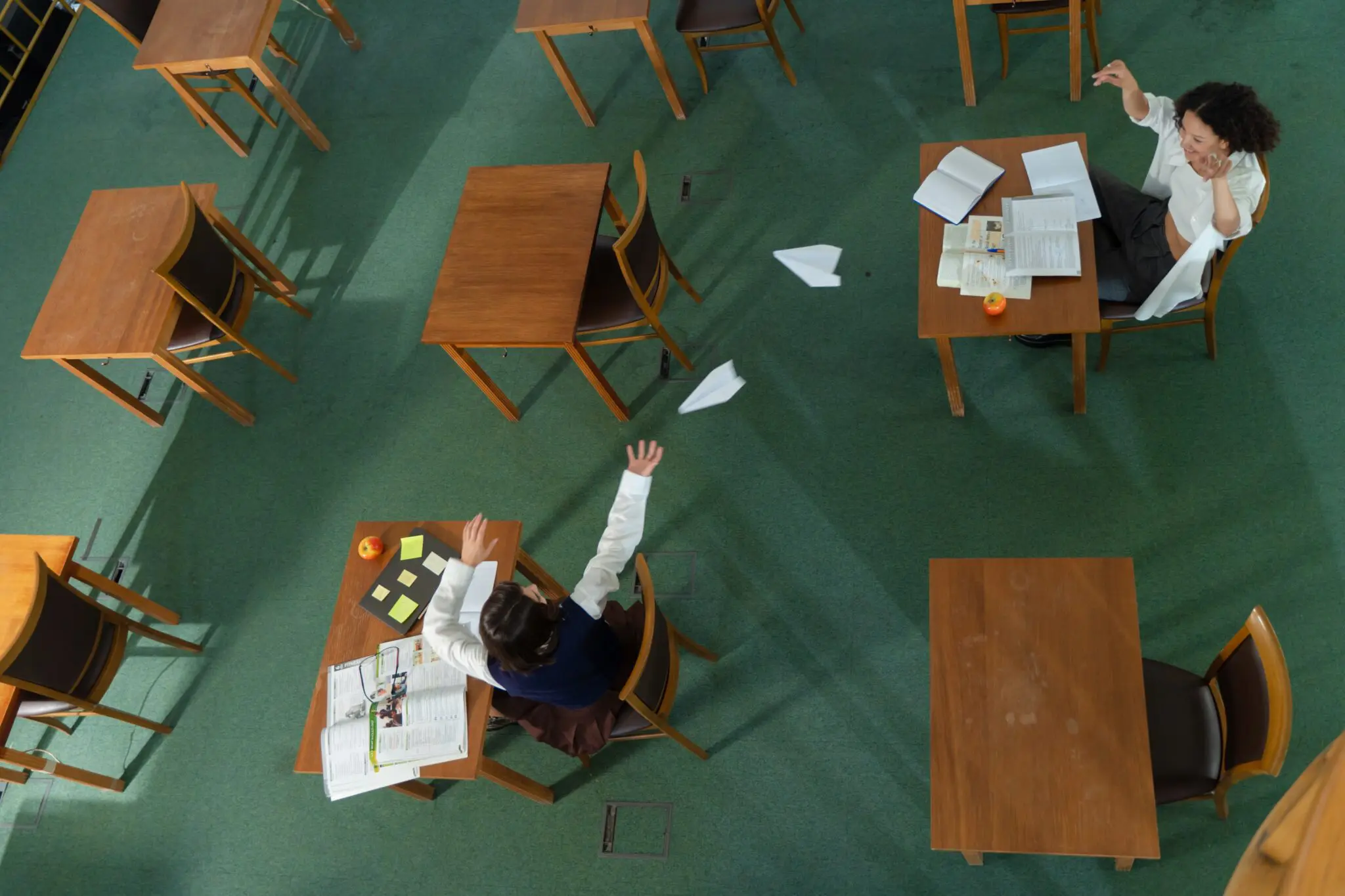 Aerial view of class room with students comparing written notes