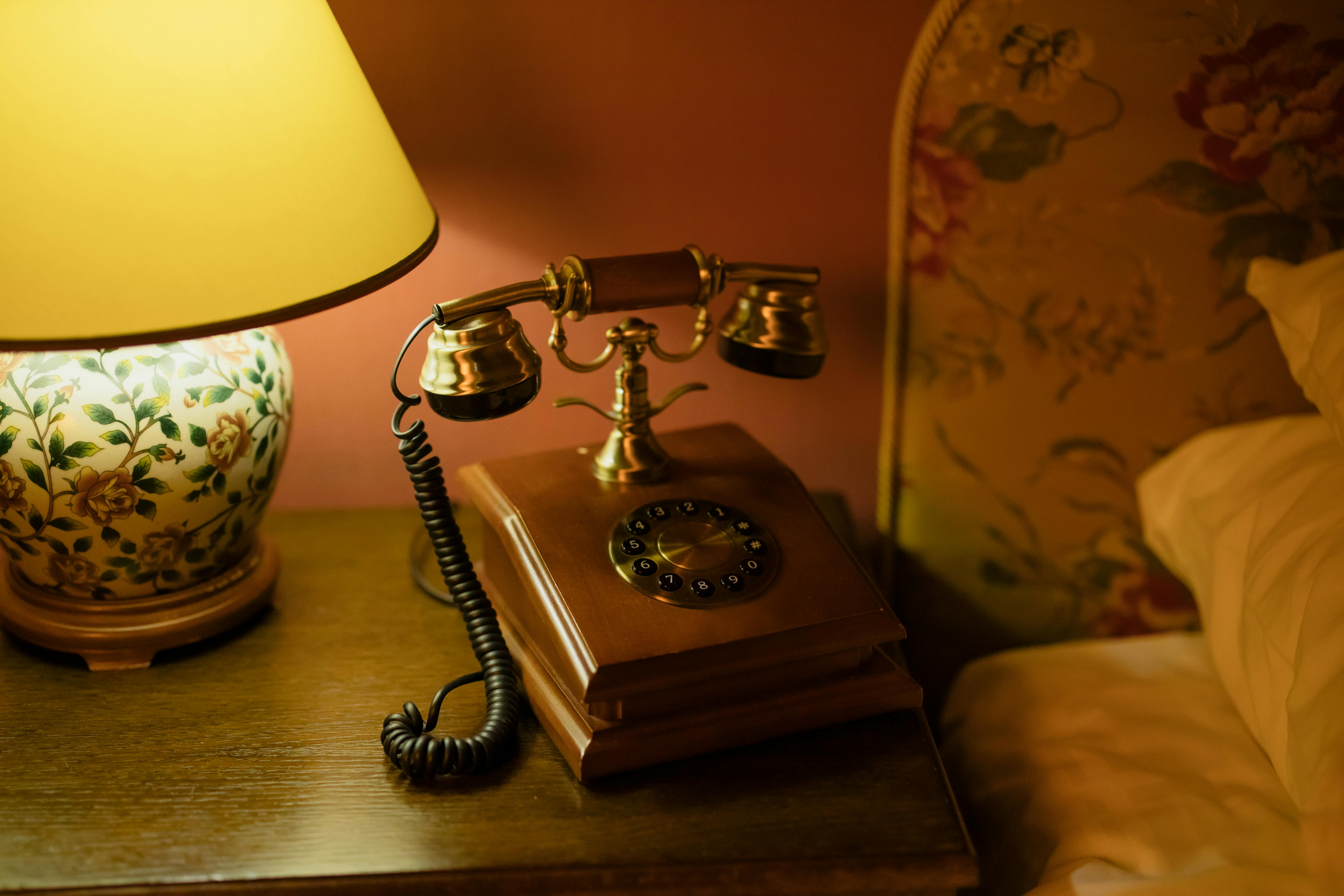 Vintage telephone placed on a bedroom side table beside the bed.