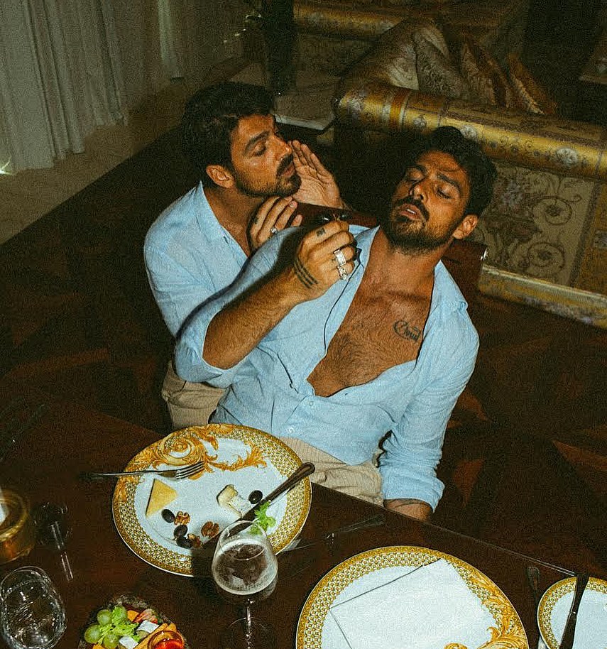 Black-and-white party photo of a smiling man in a check blazer among a crowd.