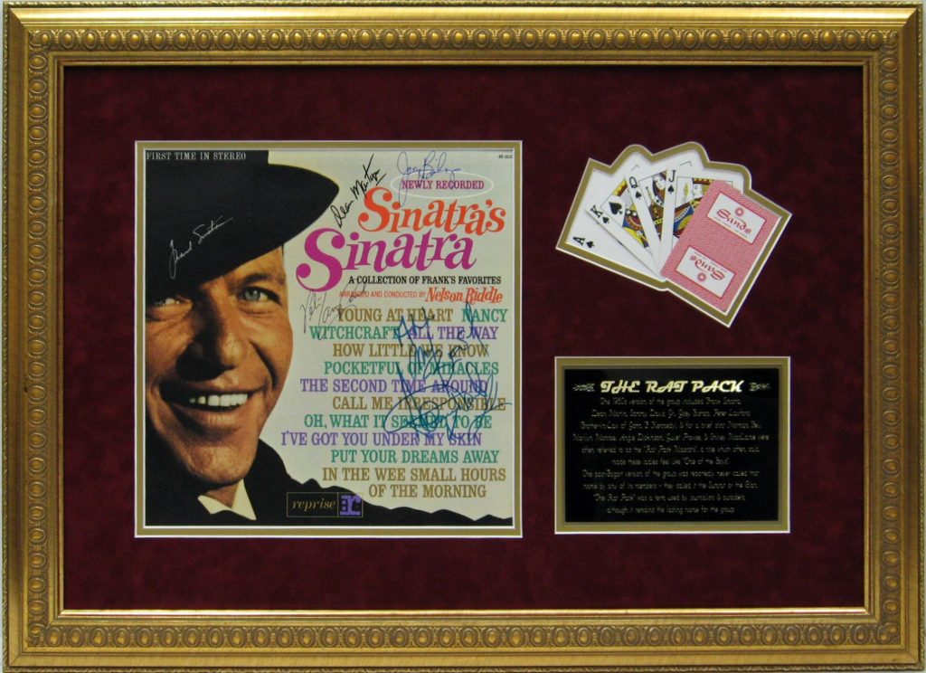 Modern glass and wood cabin with a cozy outdoor deck featuring wicker furniture, surrounded by lush green trees and a serene forest setting.