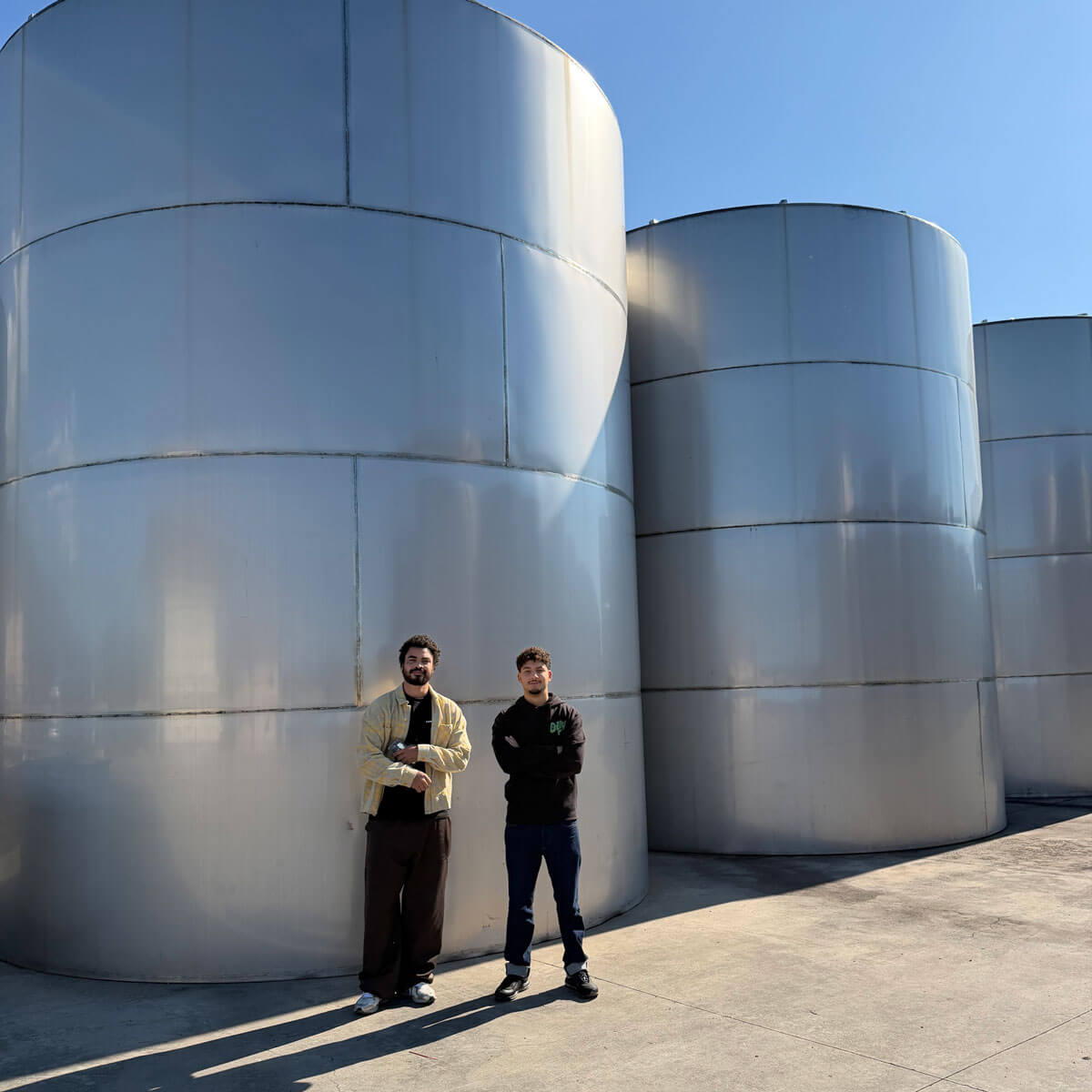 Oily founders outside two large silver vats