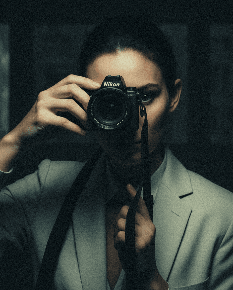 woman in a suit holding a camera in a dark office