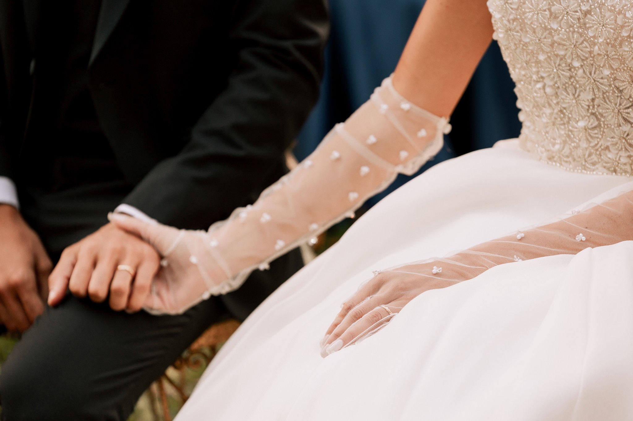 Sposi a Villa Ferrari, mani intrecciate durante la cerimonia con veli di pizzo trasparente sulle braccia della sposa
