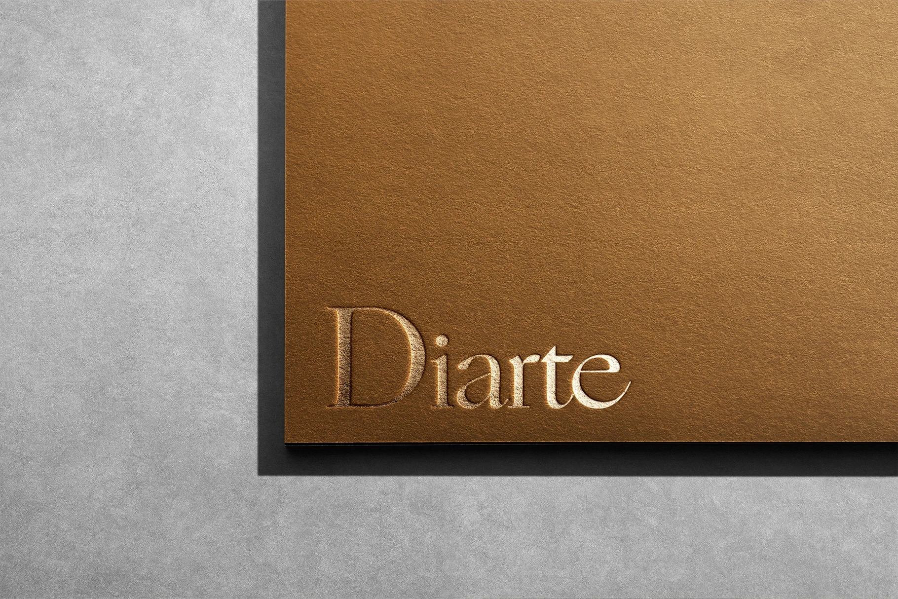 Luxury logo mockup with a debossed script font on textured gold paper.