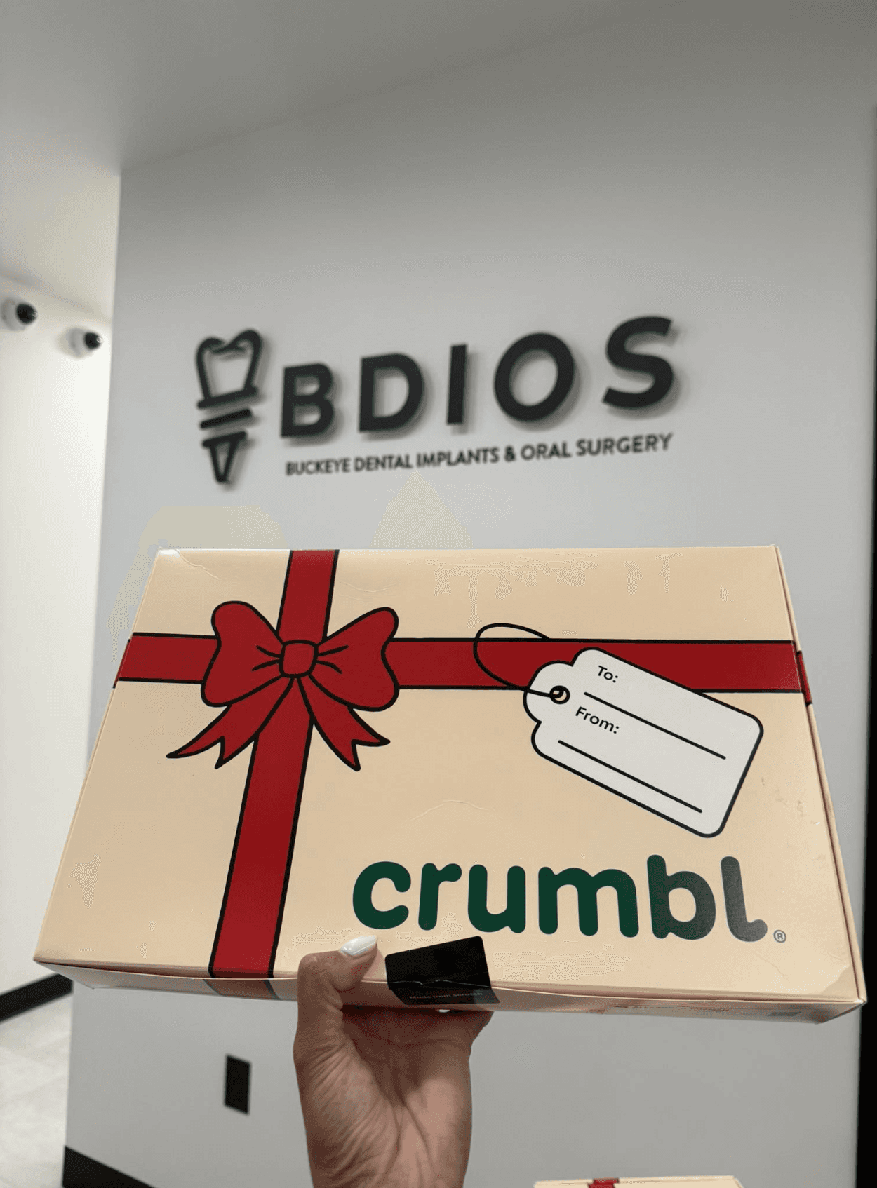 Gift box held in front of BDIOS Dental reception wall with custom dimensional logo signage.