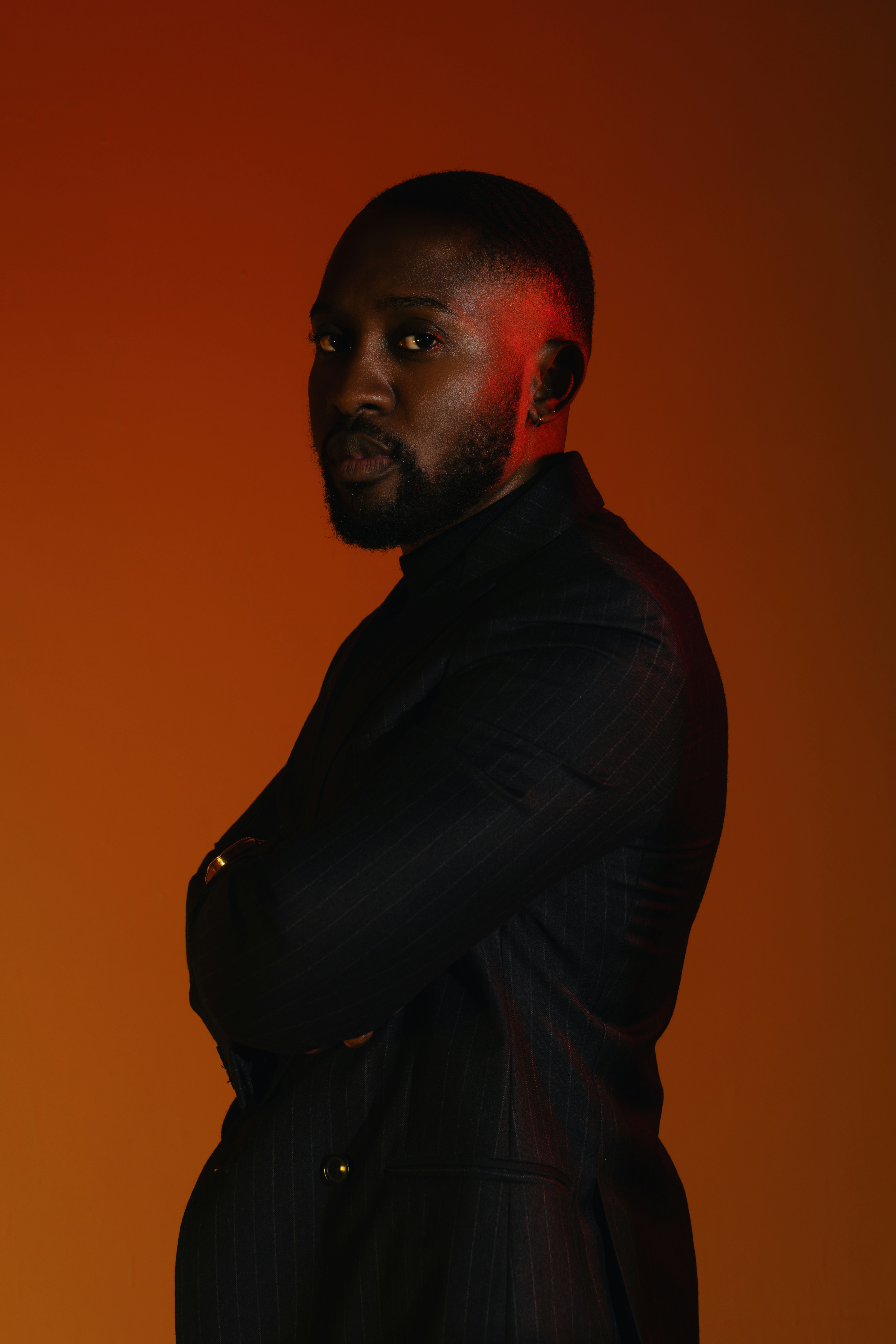 Man in a suit with arms crossed against orange background