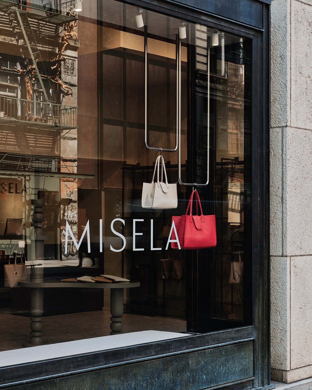 Misela storefront window on Bond Street New York featuring suspended handbag display and minimal vinyl window signage.