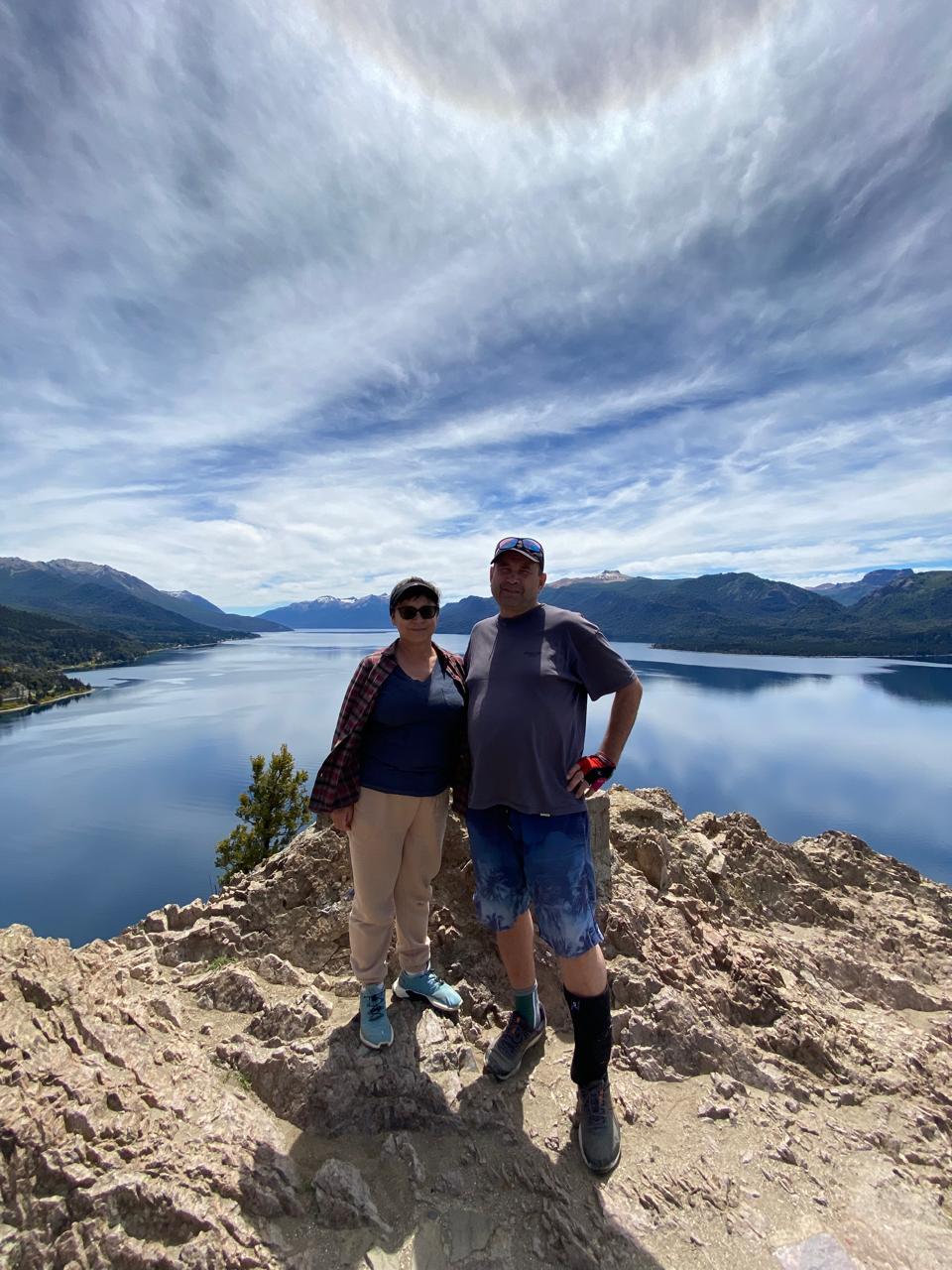Mujer sentada sobre un tronco frente a una cascada doble en un bosque frondoso de Argentina.