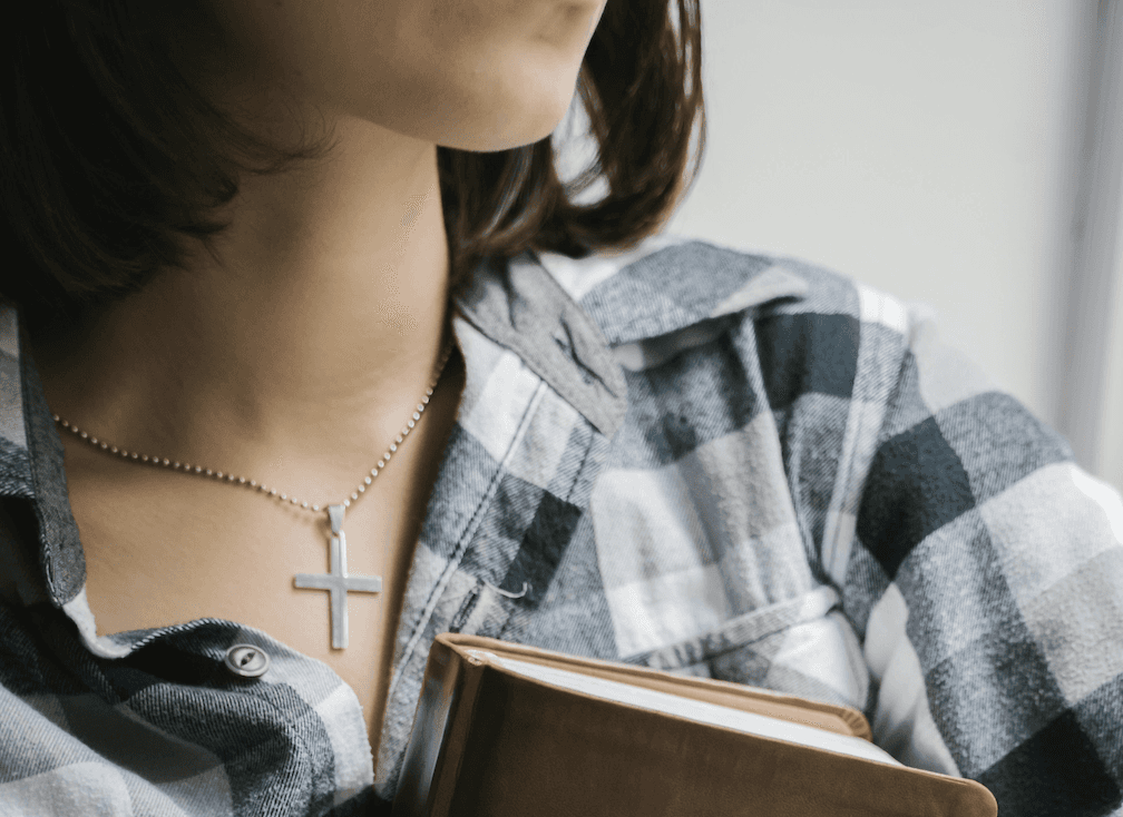 Conversion Truth for Families - Woman in black plaid top with a silver cross necklace holding a Bible