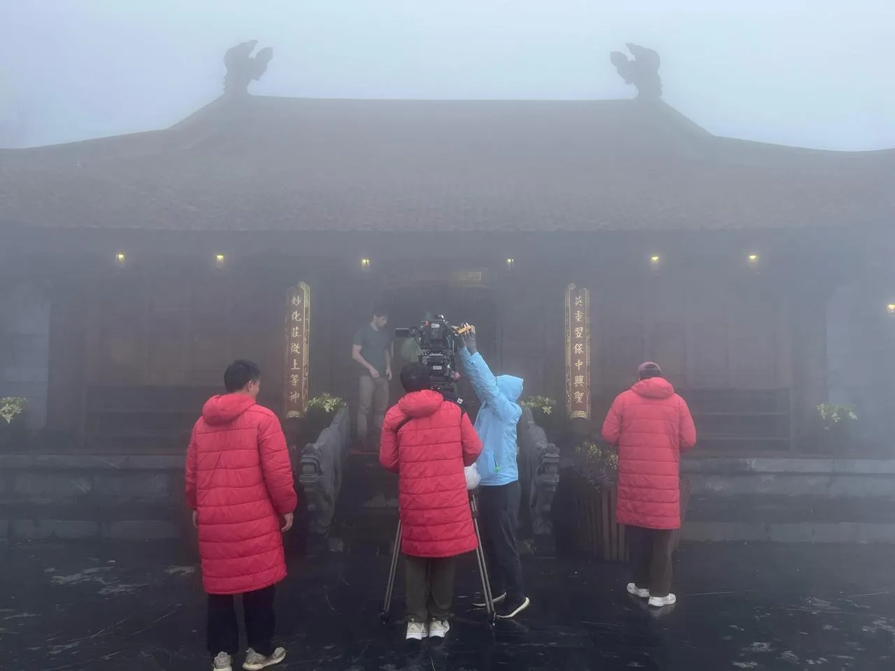 Film crew preparing a scene outside a mist-covered Vietnamese temple during production of The Last Room In Hanoi.