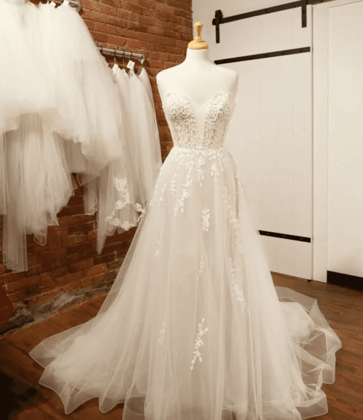 White wedding dress on a mannequin with brick wall.