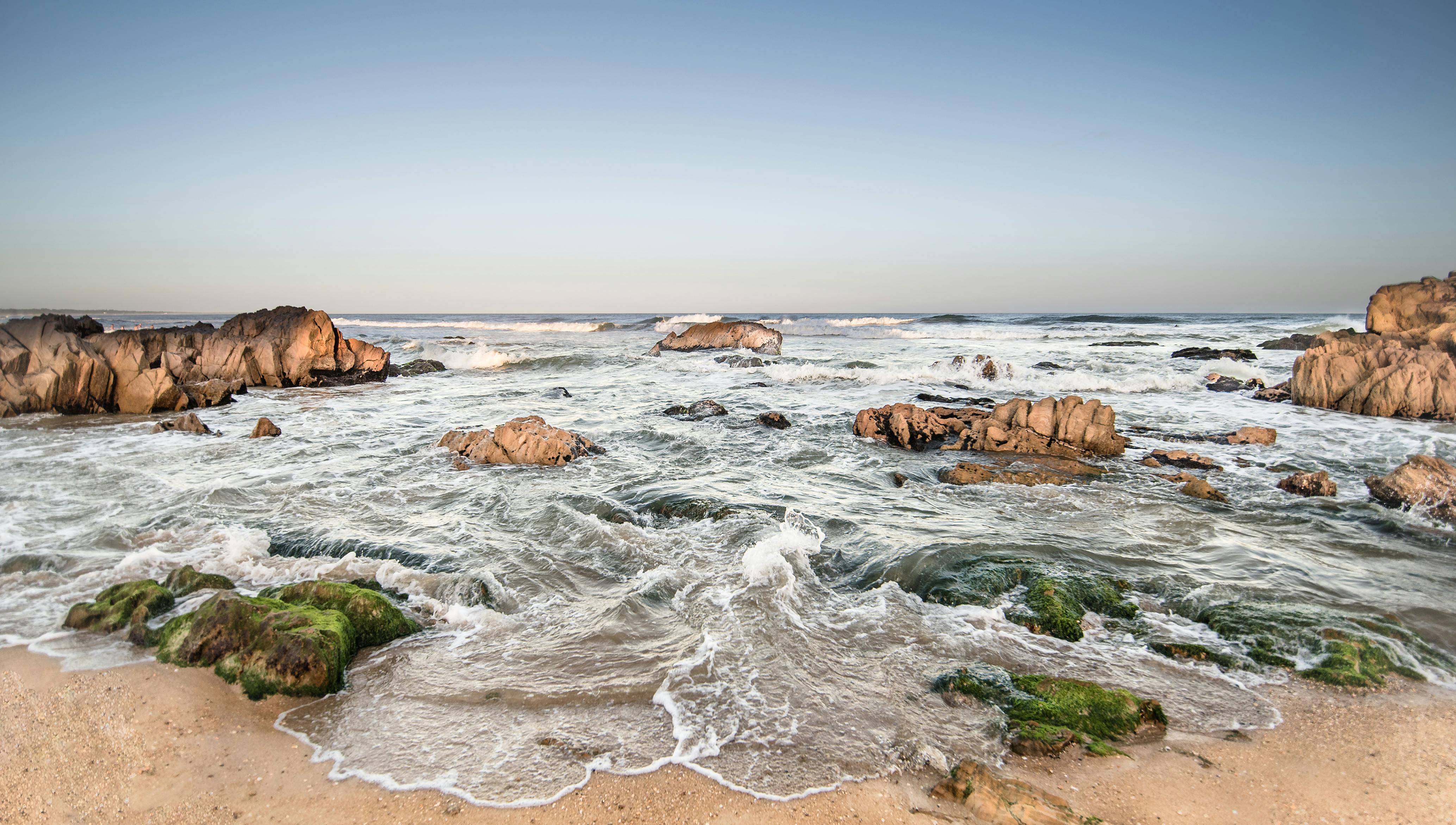 Playa rocosa con olas del océano en la costa de Uruguay, paisaje costero incluido en los itinerarios de una app de viajes.