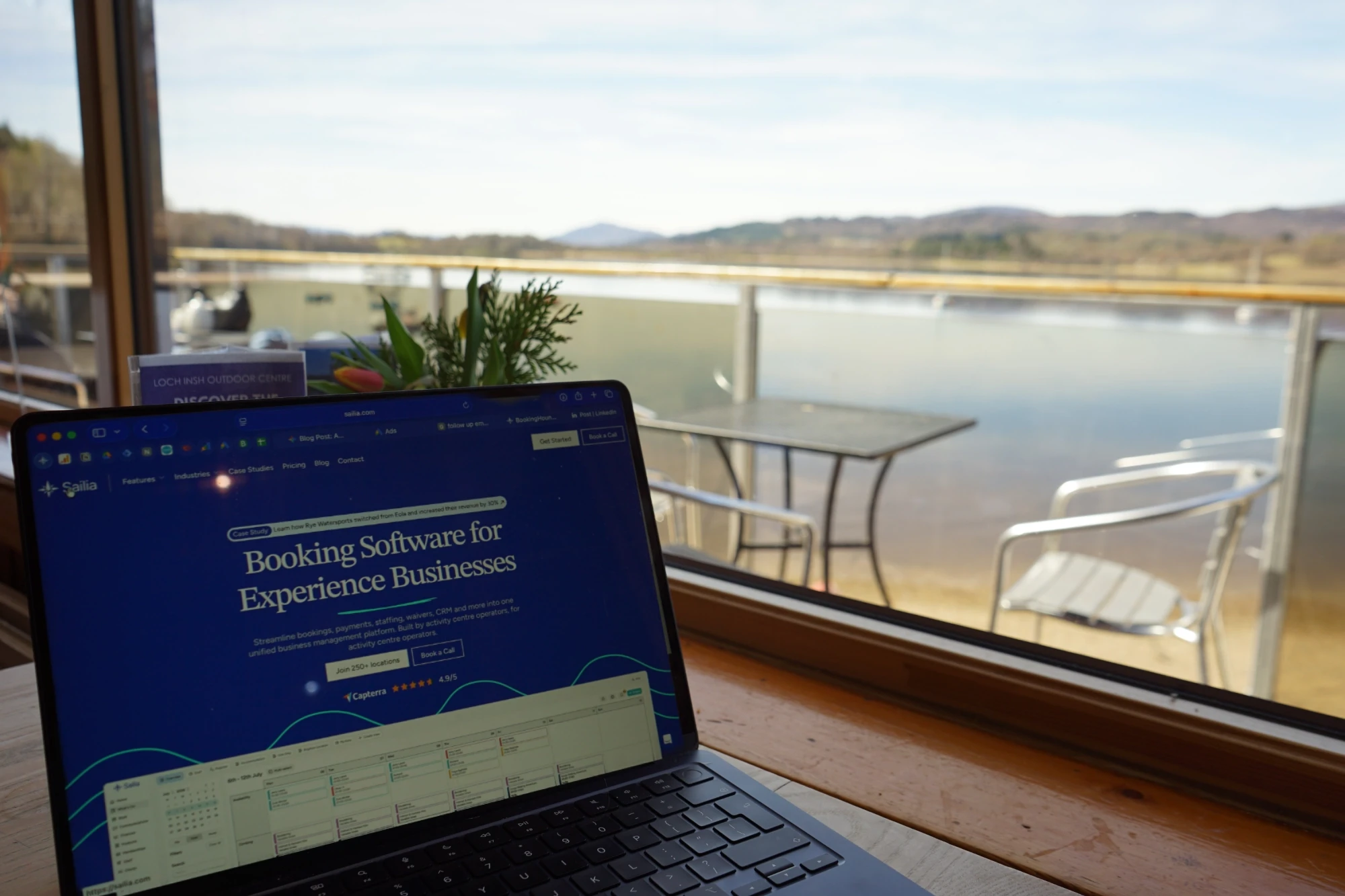 A computer on a table inside a building with a window looking out over an expanse of water