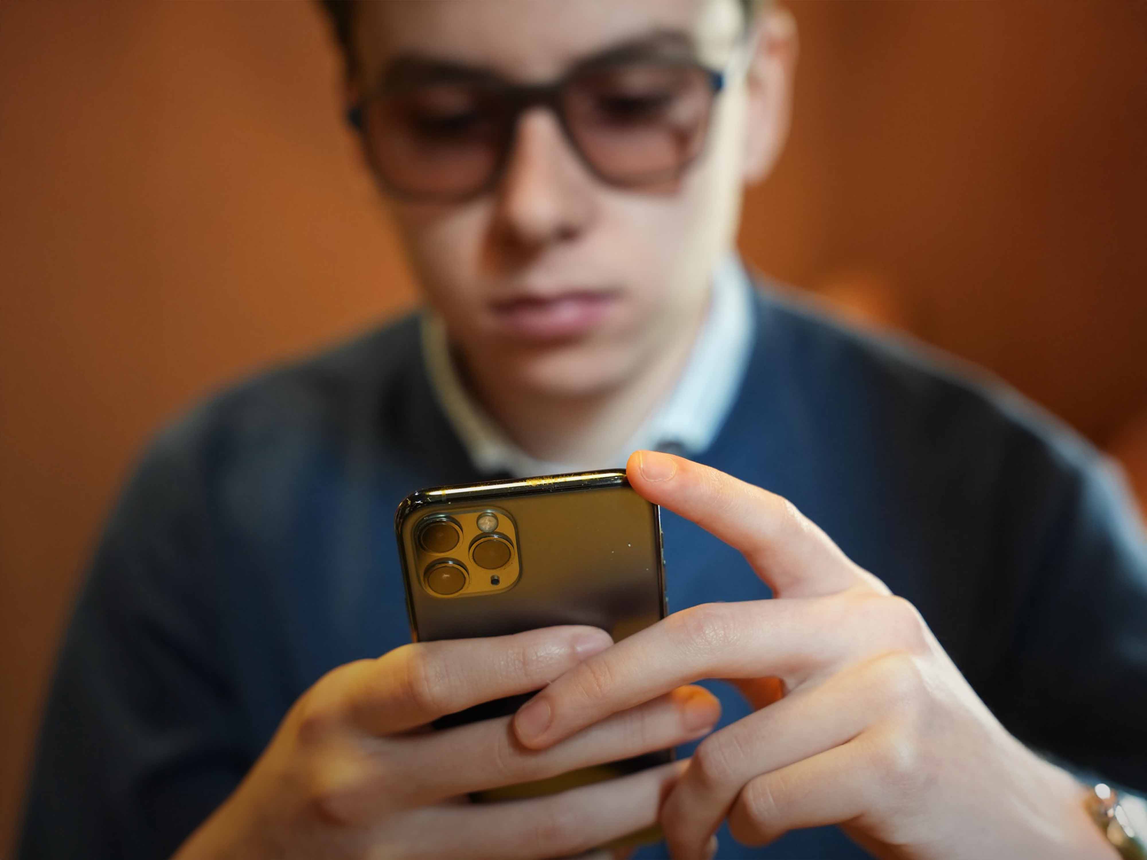 Close-up of beige and taupe-colored Slate Stride sneakers with dynamic curved sole design, worn with white socks and tan trousers, placed on a neutral-toned background.