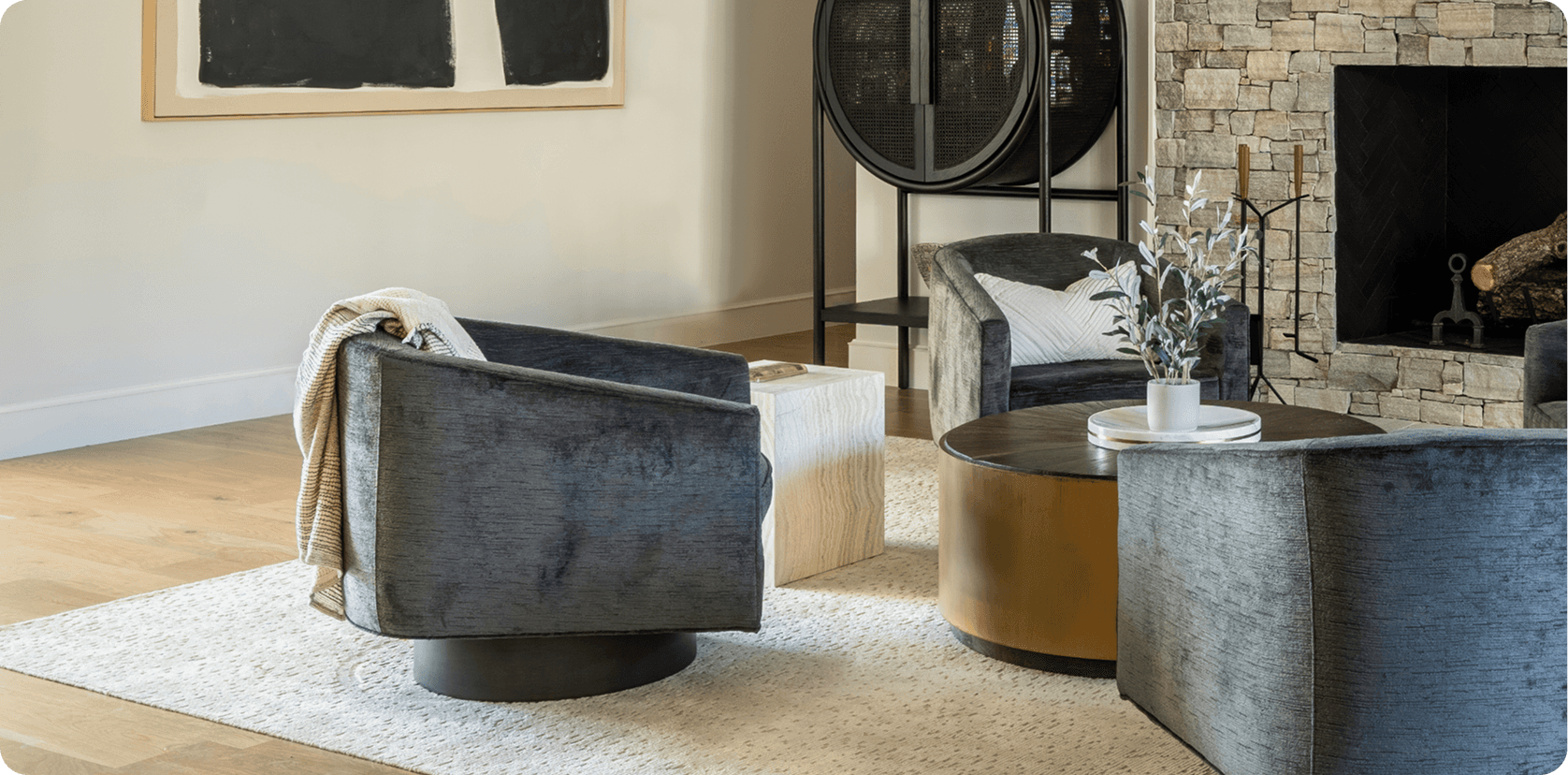 Modern sitting room with curved gray swivel chairs, round coffee tables, stone fireplace, and contemporary decor