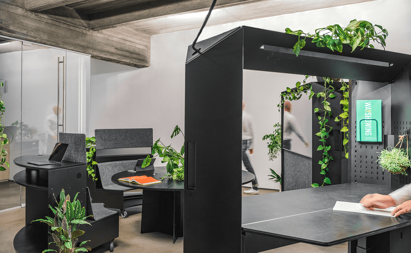 Modularer Büroraum mit dem flexiblen SCOPE System, inklusive Transformationswand mit Bildschirm, Steh-Arbeitsplatz, rundem Tisch, Pultbänken und vielen Pflanzen – gestaltet von Design for Human Nature in Hamburg.