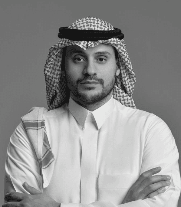A serene portrait of a young woman with short dark hair, wearing a light, semi-transparent blouse against a soft, blurred background.