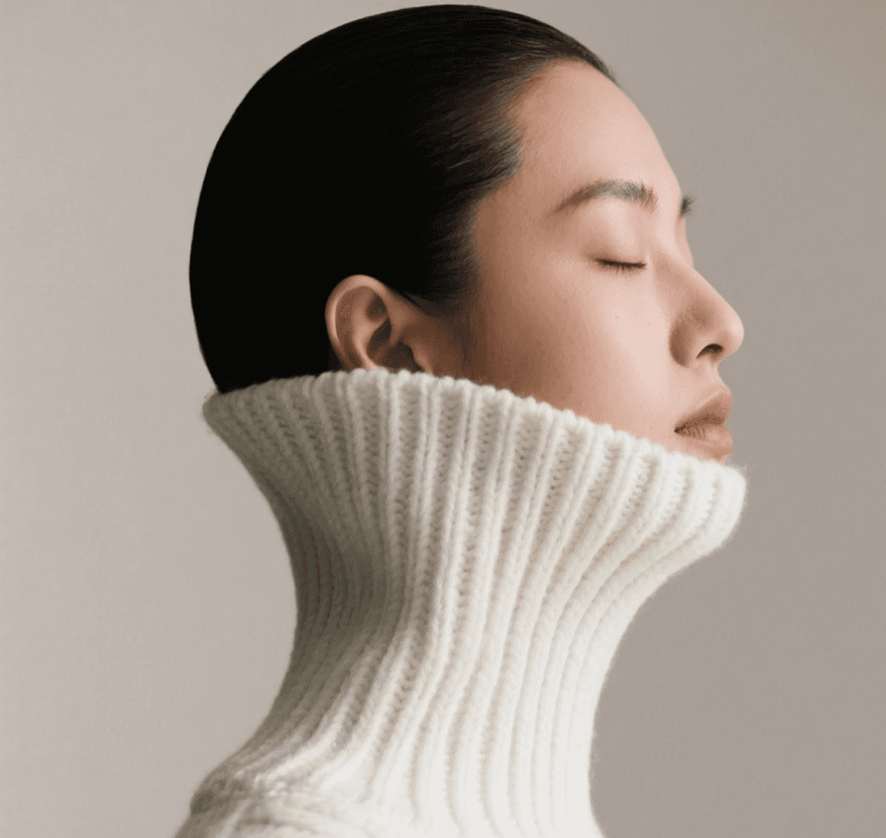 Asian woman in white turtleneck sweater with eyes closed
