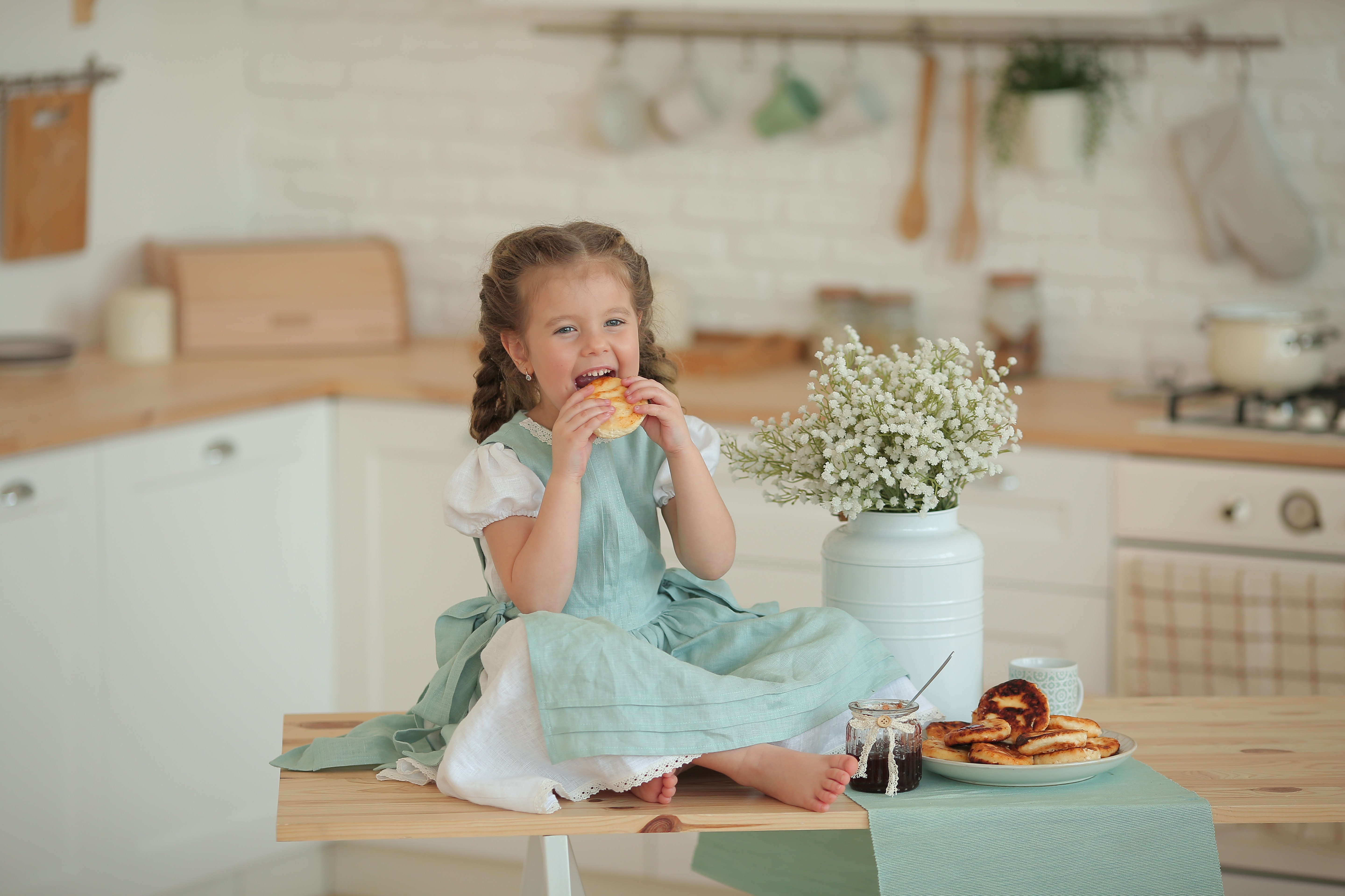 Child eating a snack in a cozy kitchen before a photoshoot
