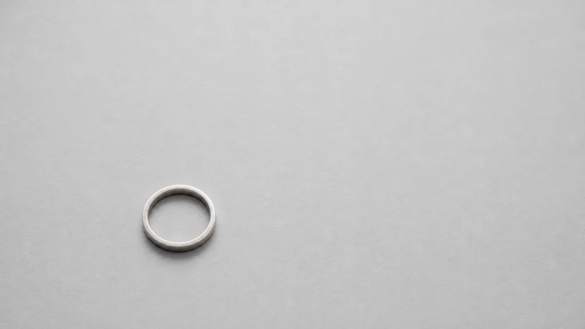 Plain silver dhikr ring on cool-grey paper with generous negative space