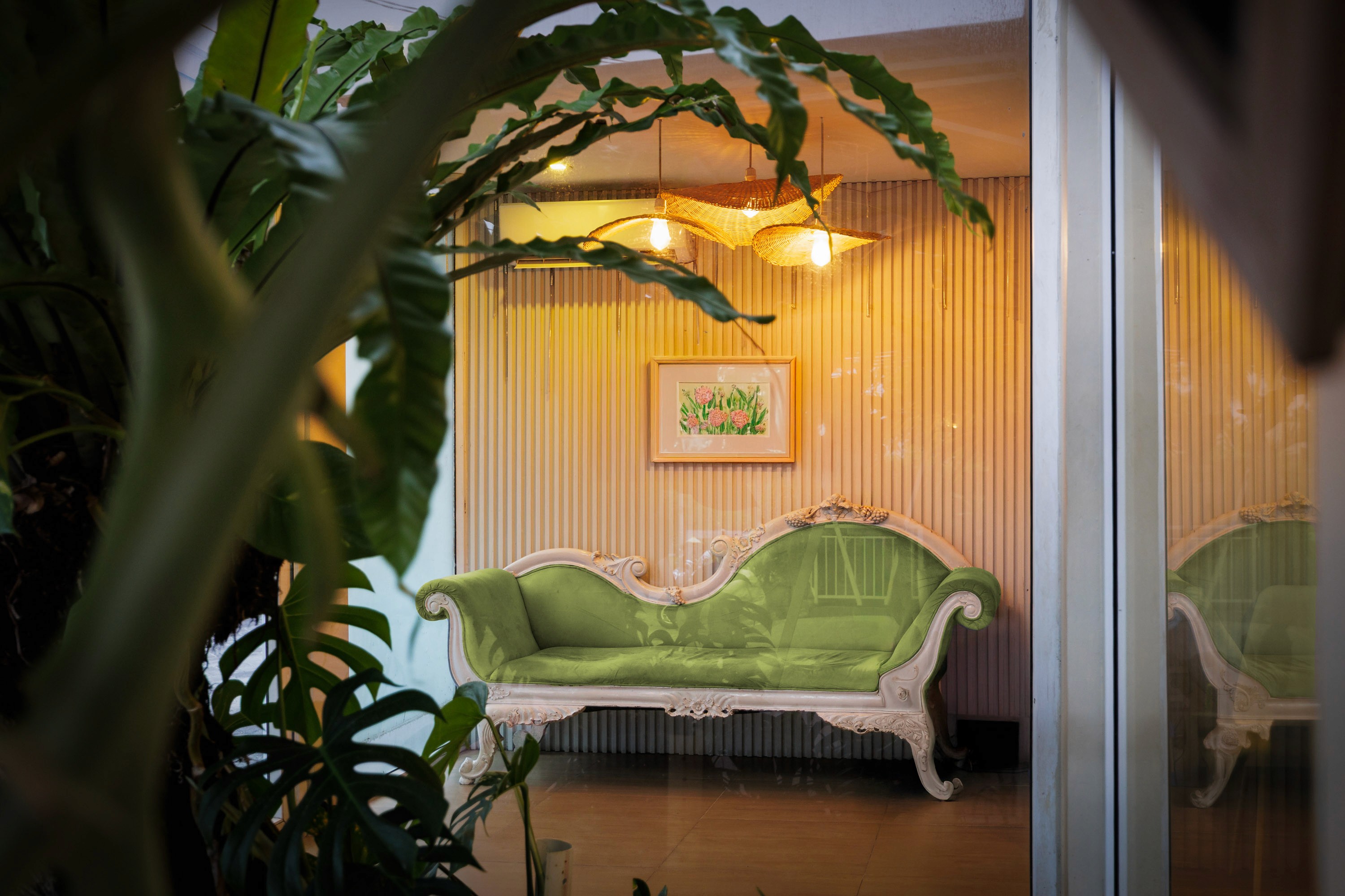 “Lobby seating area with green sofa and rattan lights, Bali apartment”
