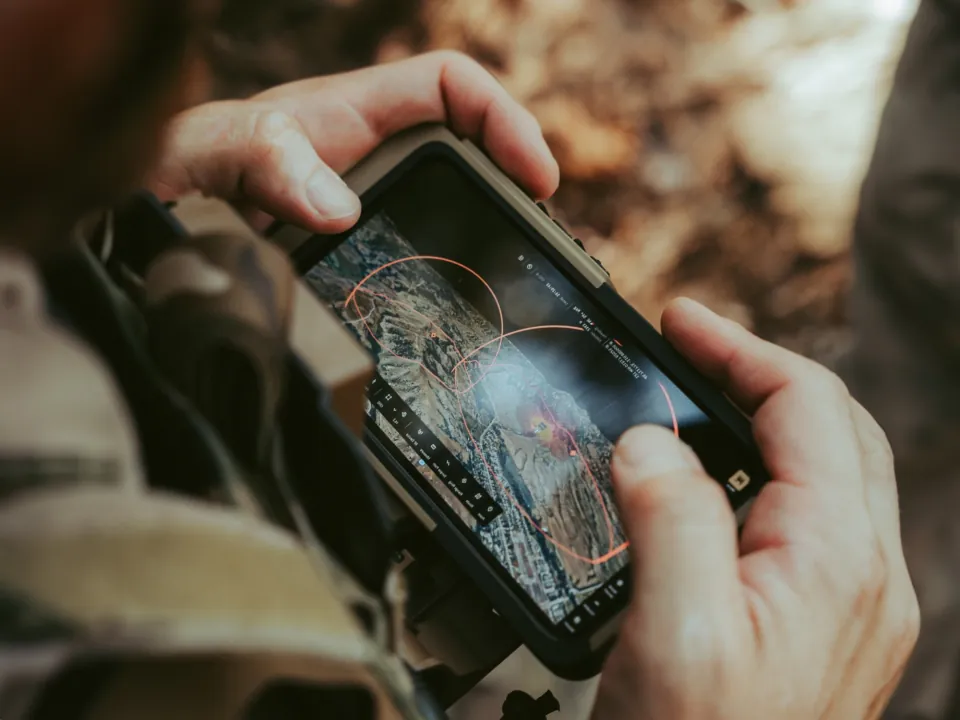 Operator holding a rugged handheld running Farsight with range rings over terrain