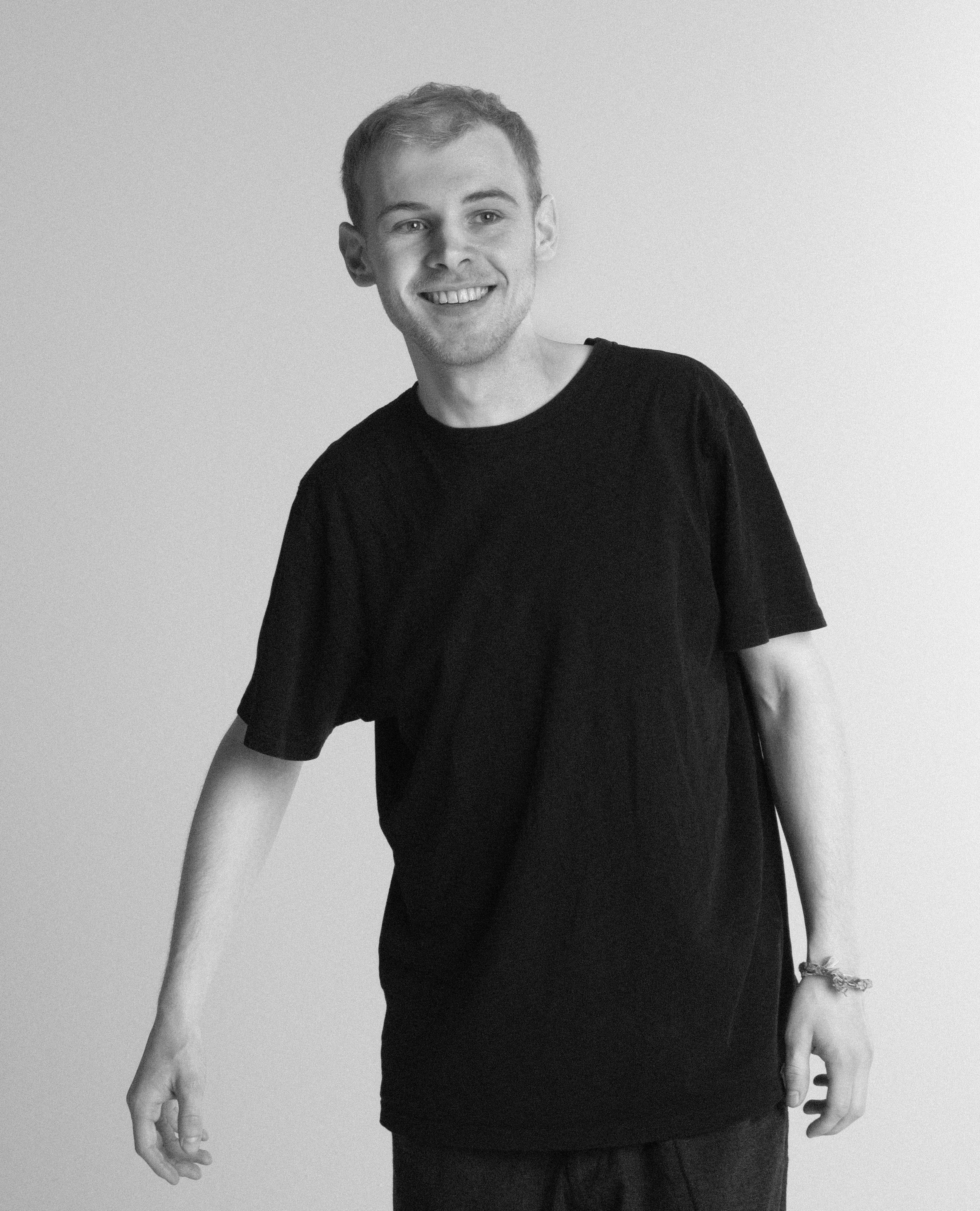 A thoughtful young person with dark hair gazes to the side, captured in soft black and white lighting.