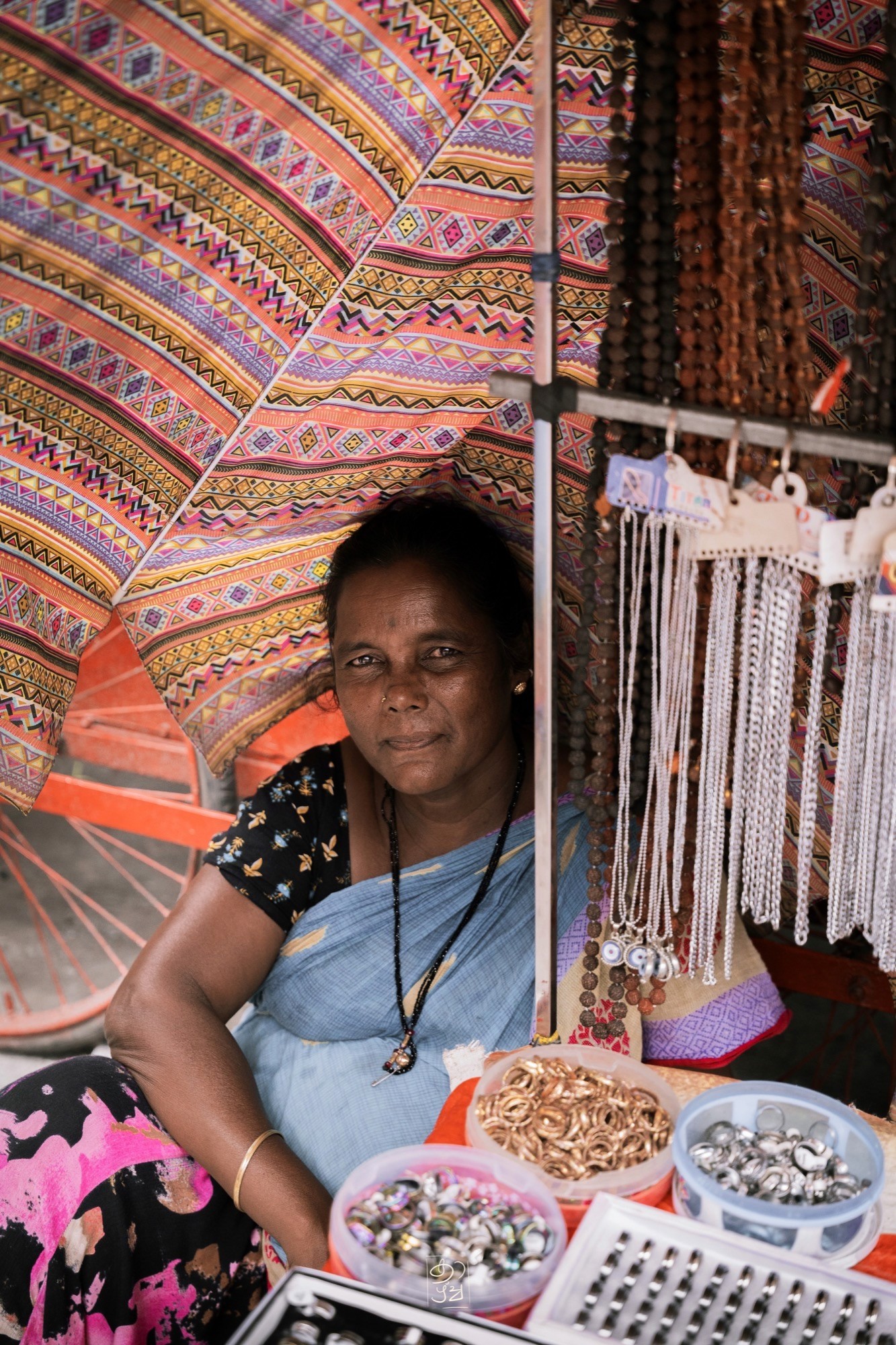 A woman at her bangle stall under a patterned umbrella