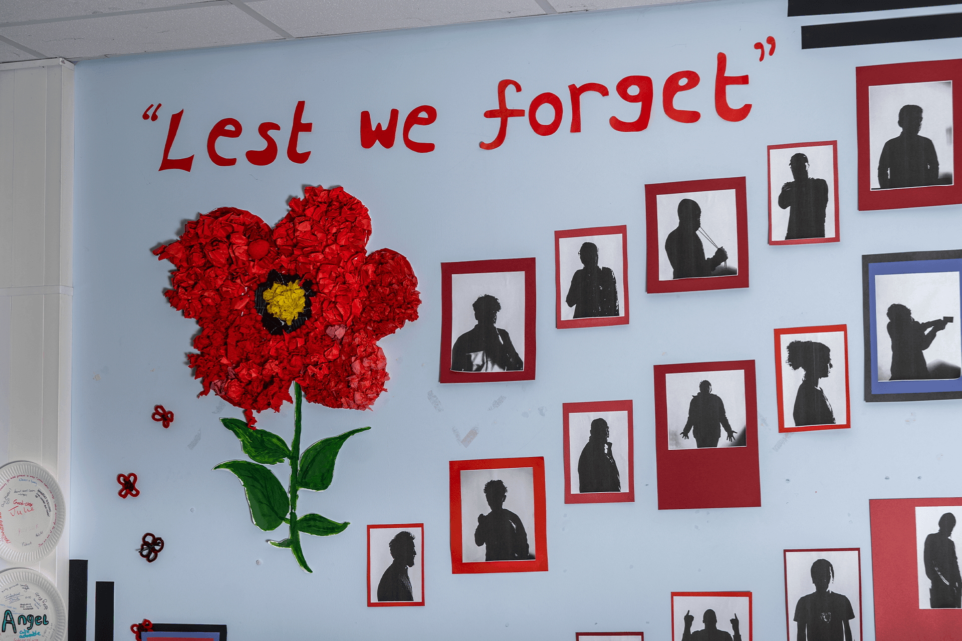 Bulletin board featuring a red origami flower and the phrase 'Lest We Forget', in commemoration and remembrance