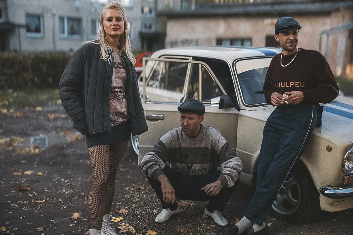 Three gopniks in 90s street style posing with a Soviet retro car in Southern Chronicles, a nostalgic Baltic comedy-drama about youth and identity.