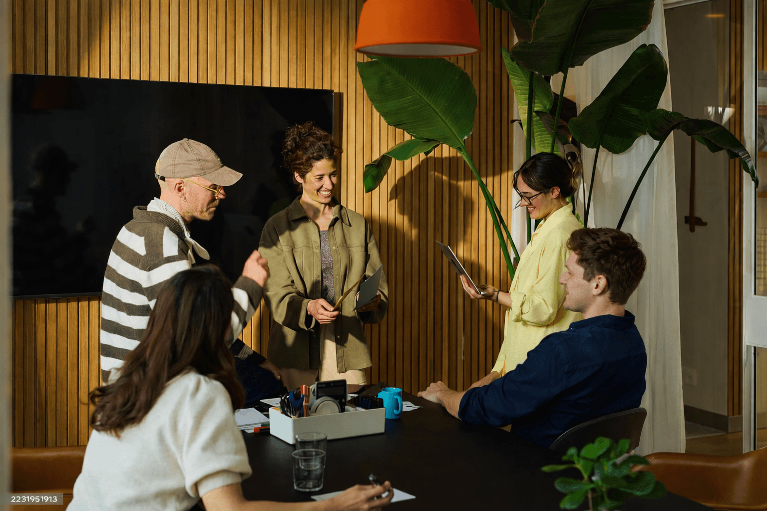 Sculptural display of curled, tan leather-like material rolls arranged on a wooden block with dried wheat stems, set against a beige background.
