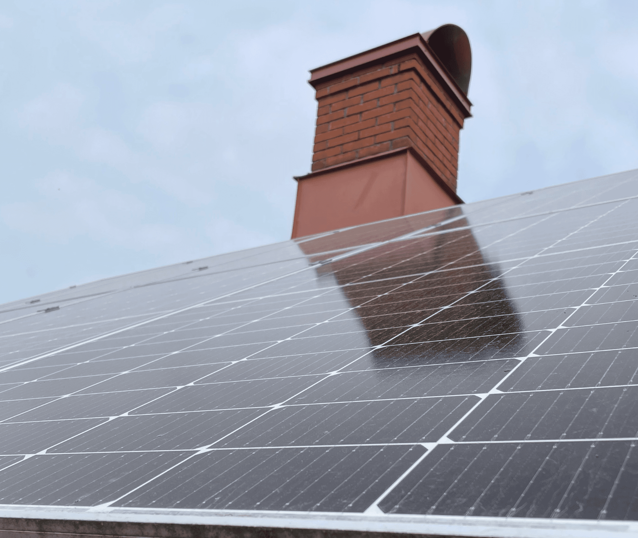Bild på ett hustak med smutsiga solceller och en skorsten
