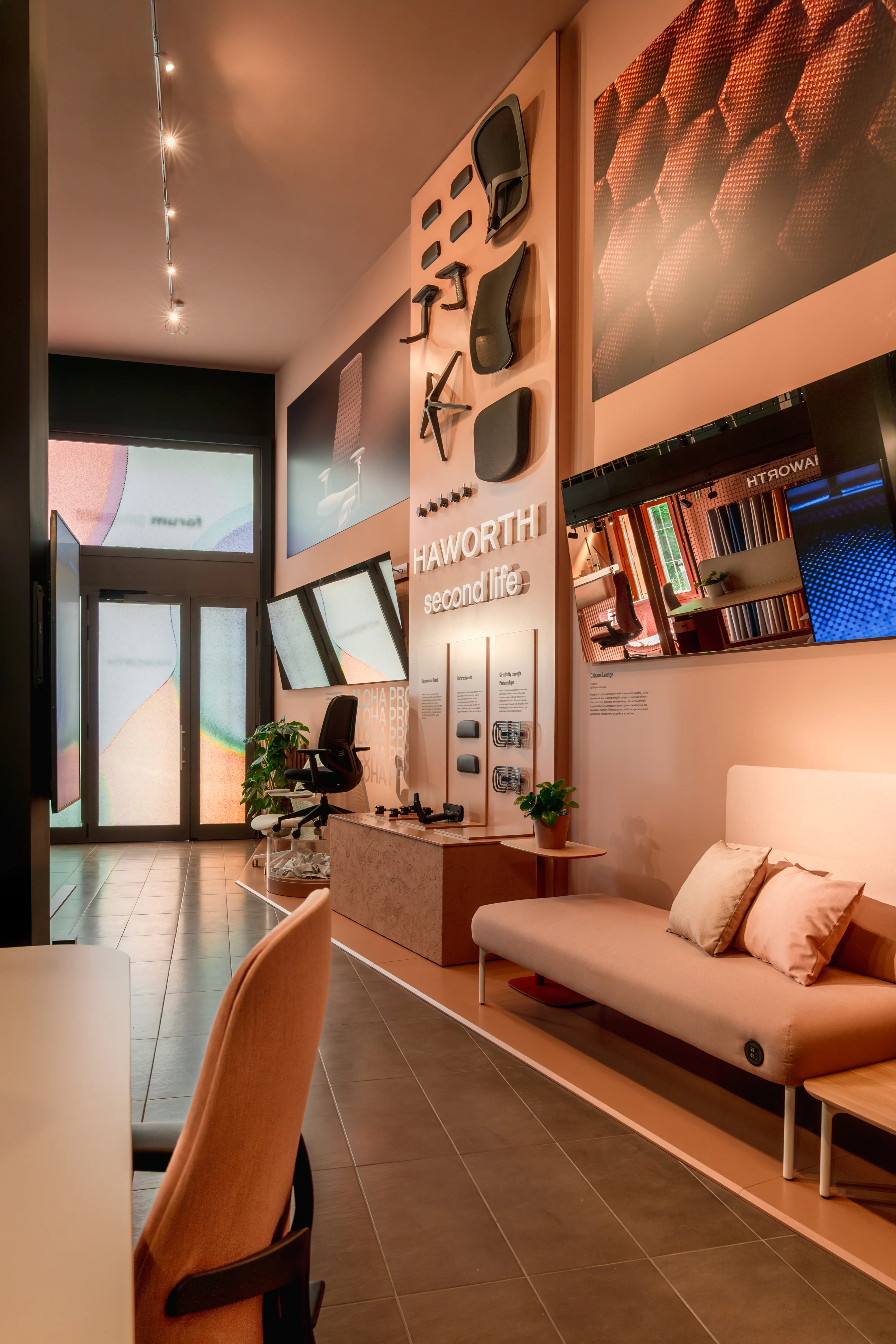 Haworth Second Life area with wall-mounted chair components, sofa and warm peach tones in the showroom.