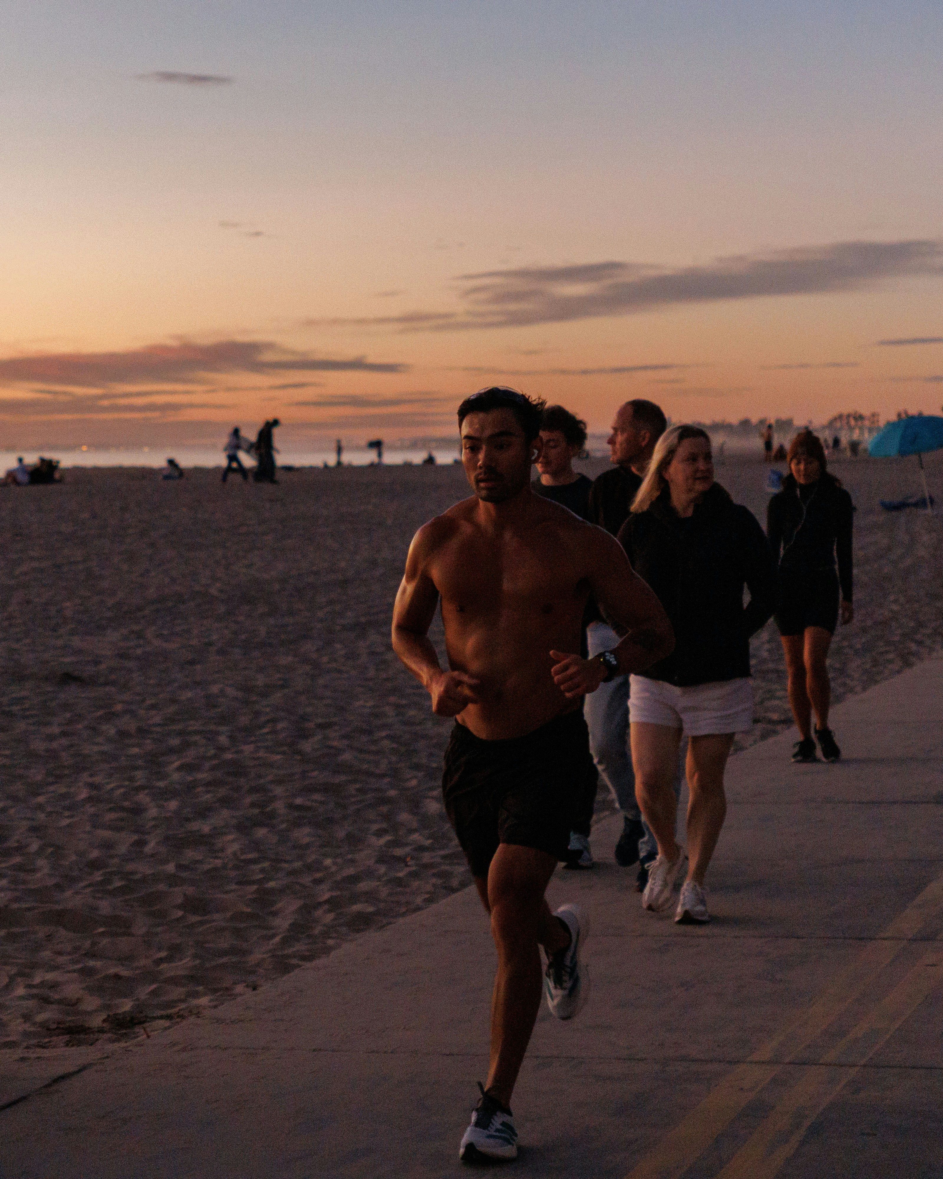 People jogging on a beach path at sunset