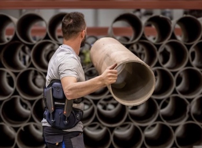 Un homme portant un exosquelette Japet.W+ soulevant de cylindre