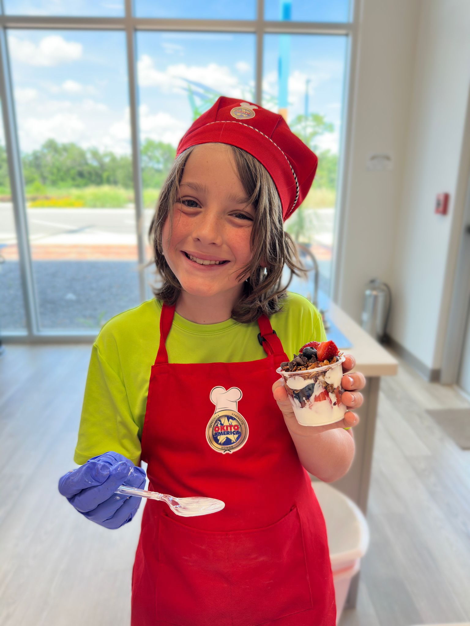 Children holding a parfait they made in cooking class, smiling at the camera.