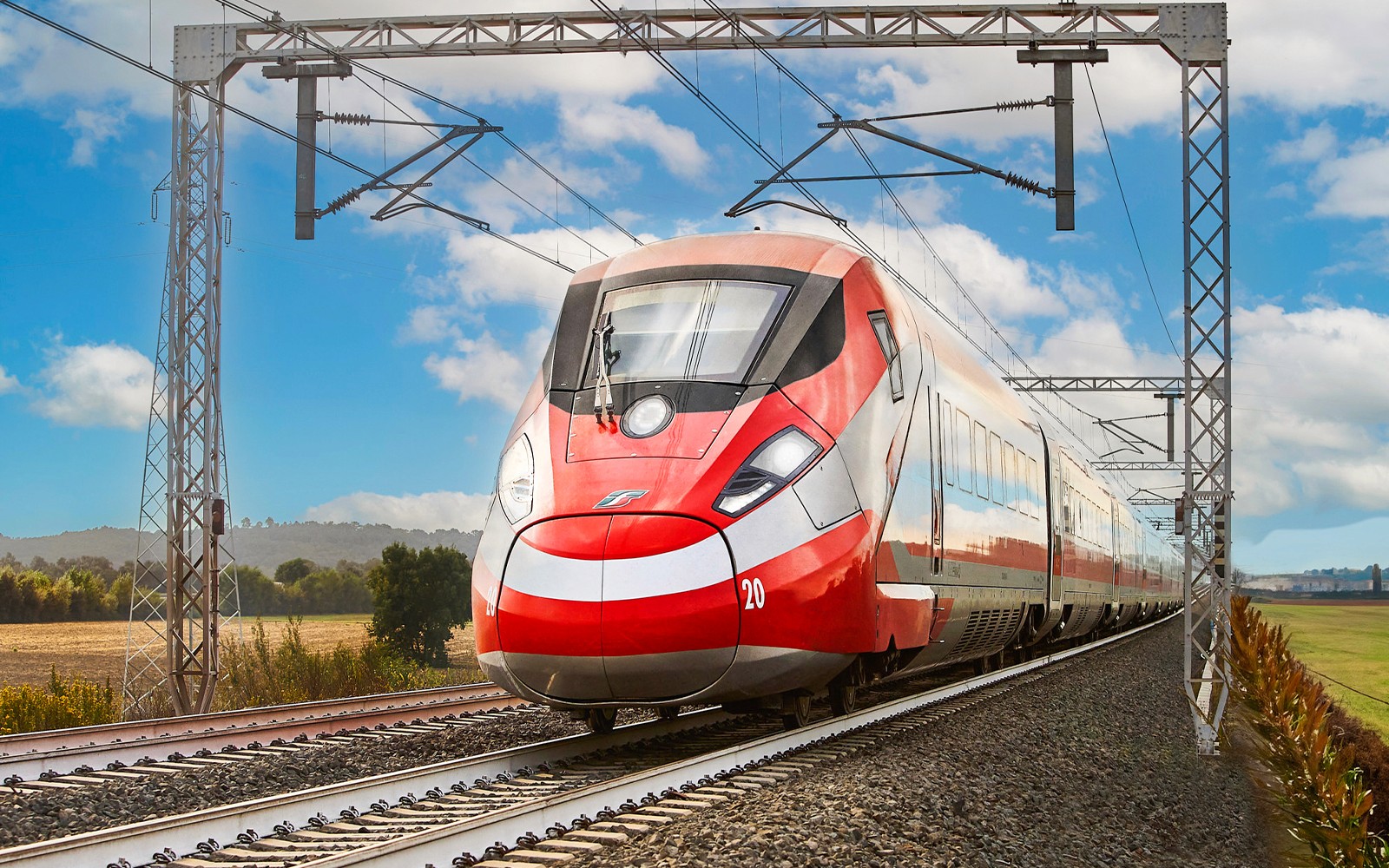 Trenitalia train traveling through Italian countryside under blue sky.