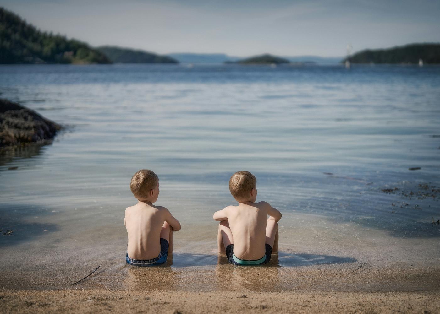 Twin boys sat together by the seaside