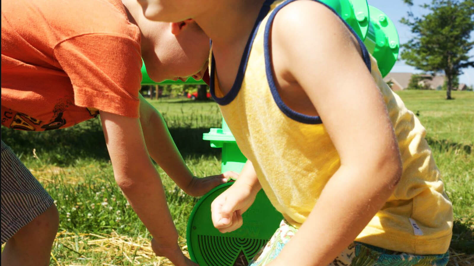 Children play with large neon green pipes that appear to weave in and out of the grass. The pipes turn groundwater data into music. And the music plays when the kids interact with the pipes. 