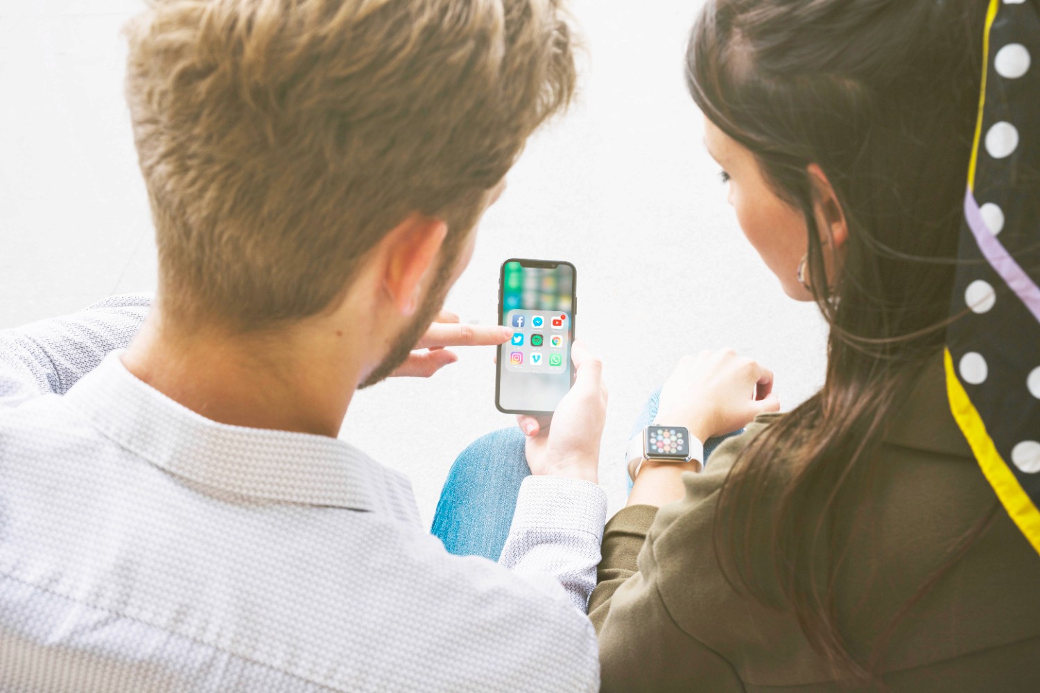  A man and woman are engaged in conversation while examining a smartphone together.