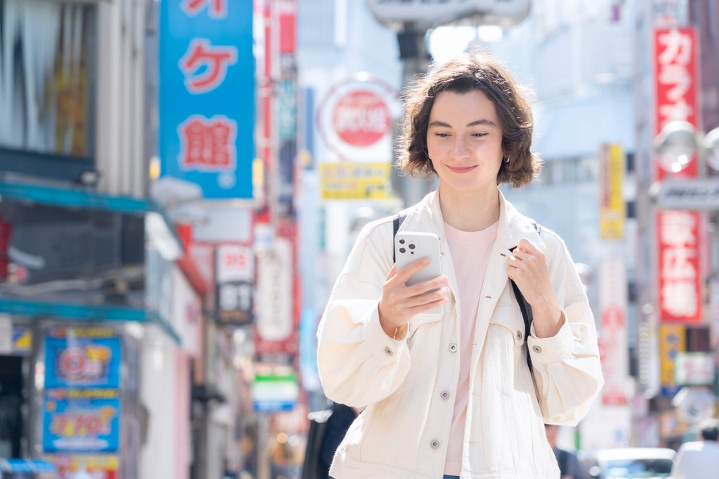 Young, foreign women solo-traveler walking the streets of Tokyo, using their Journey Japan eSIM Data Plan