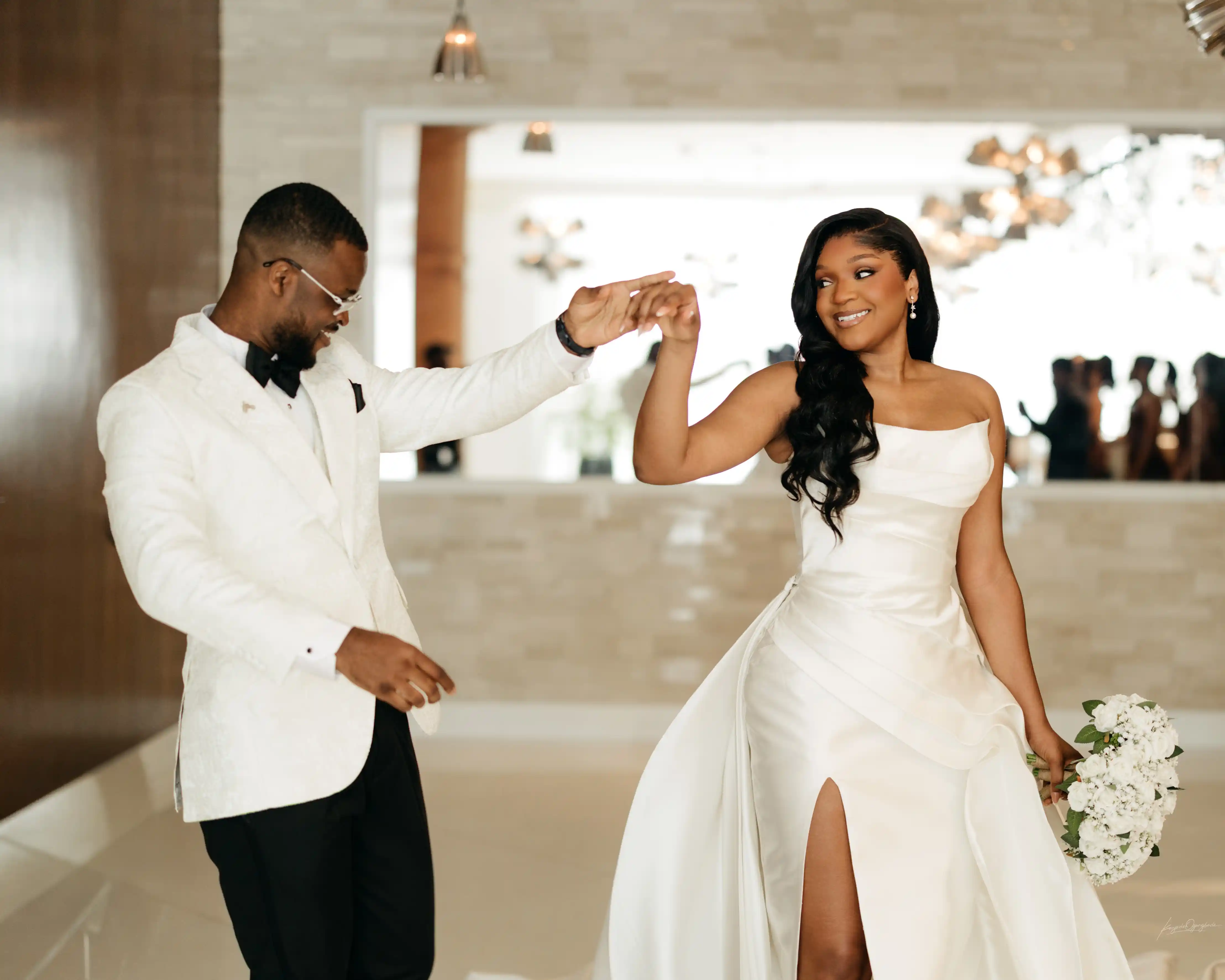 A couple joyfully celebrates in front of a rustic stone building.