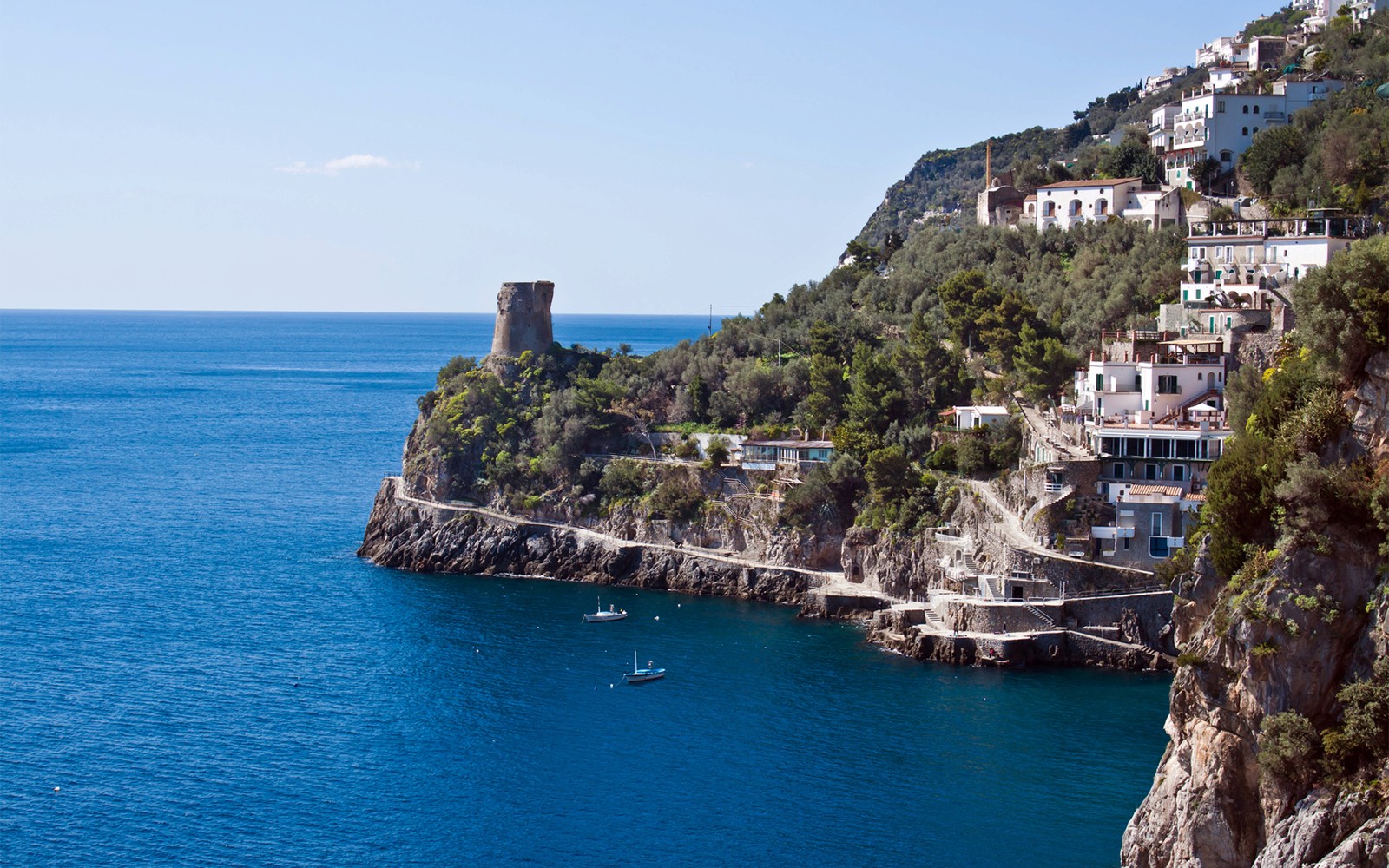 Klippkusten vid Amalfikusten med båtar och ett historiskt torn på en heldags båtutflykt med skeppare.