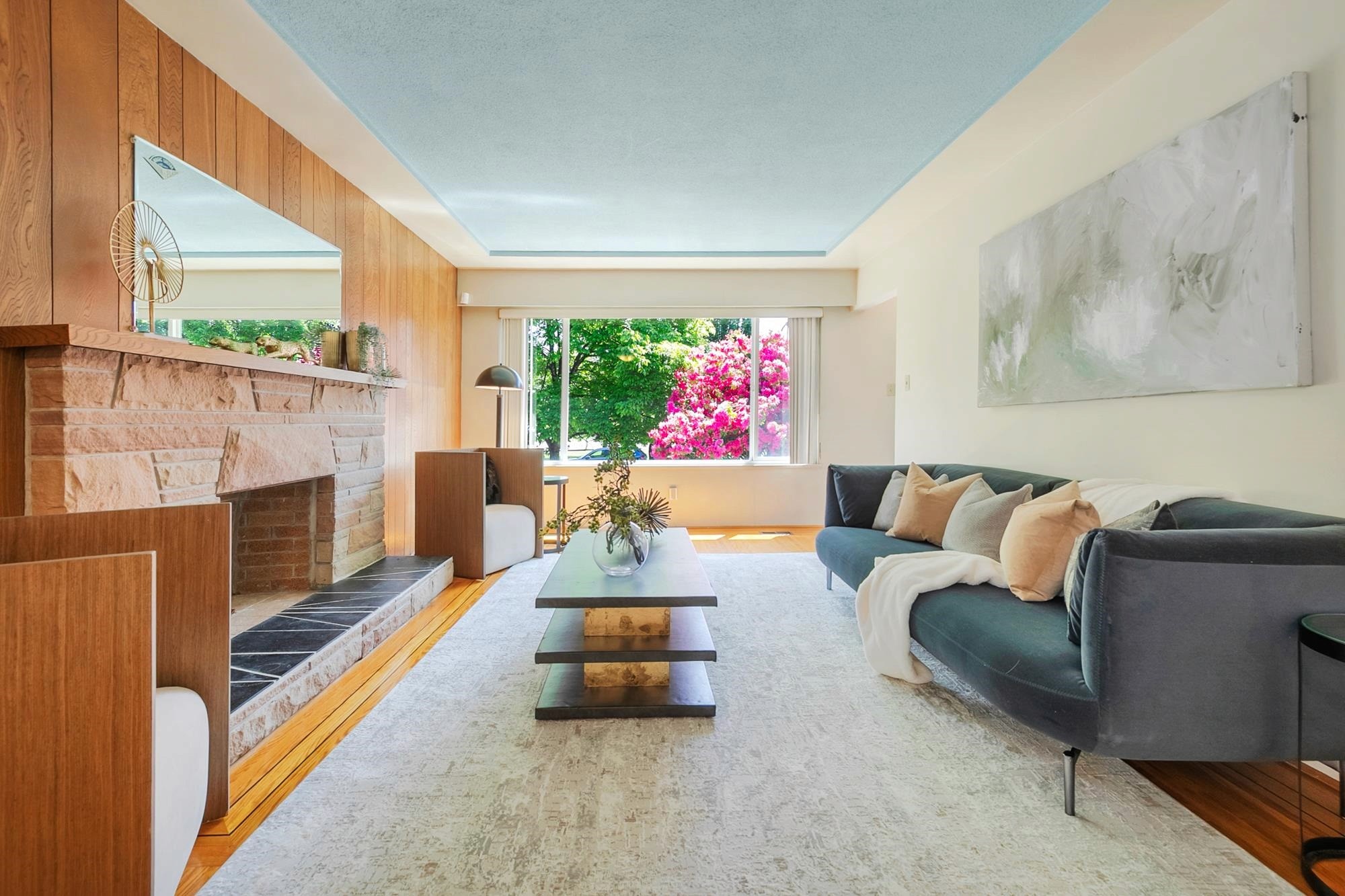 A bright living room featuring a cozy seating area, large windows, and green plants, creating an inviting atmosphere.