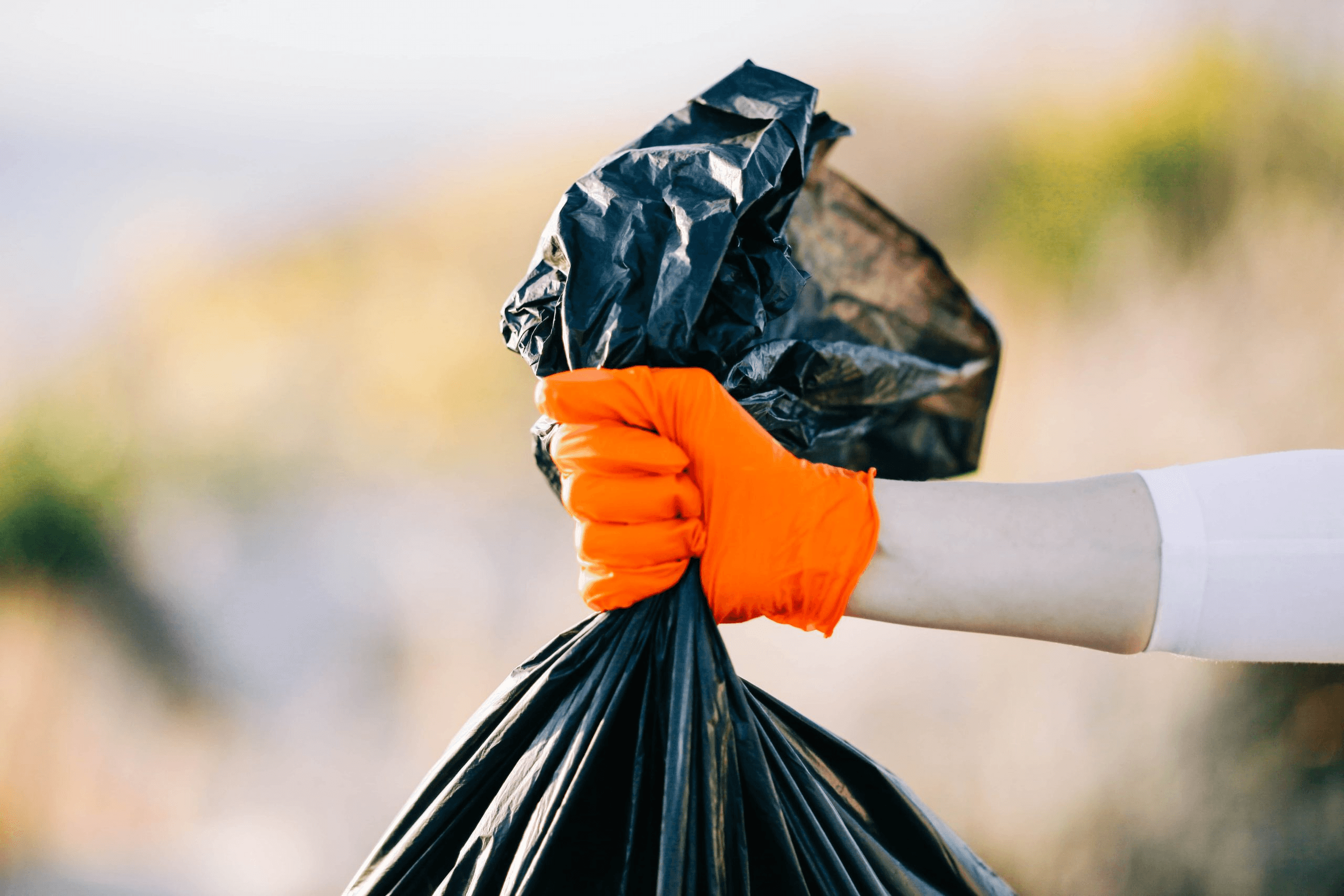 An image of a hand carrying a trash bag