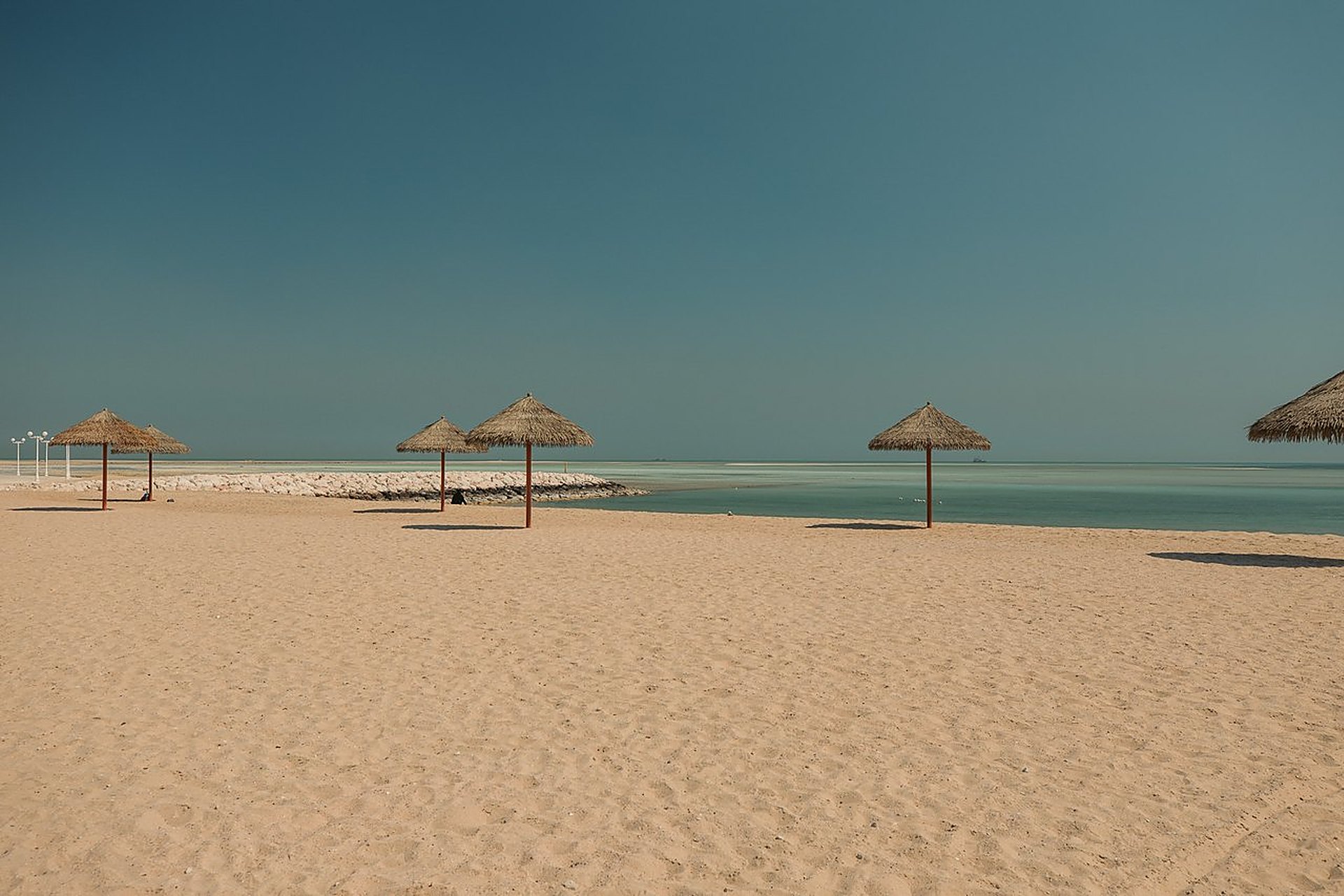 La plage d'Al Wakrah, au Qatar, ses parasols de palme sur le sable et sa mer turquoise, pour les week-ends en famille