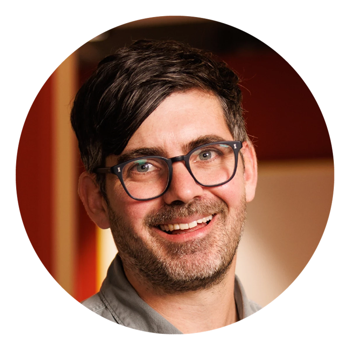 A circular portrait shows a person with short dark hair in a warm, indoor environment. Soft lighting and muted colours create a professional feel.