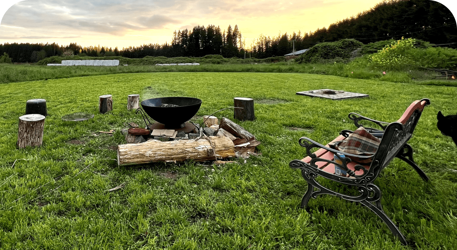 An outdoor gathering area with chairs and a fire pit set in open land at Rooted Northwest.